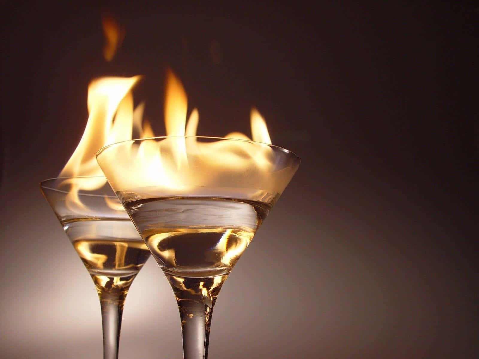 alcohol 桌布 壁紙 — 兩個馬提尼杯裝滿燃燒的金色液體，背景為深色漸變。