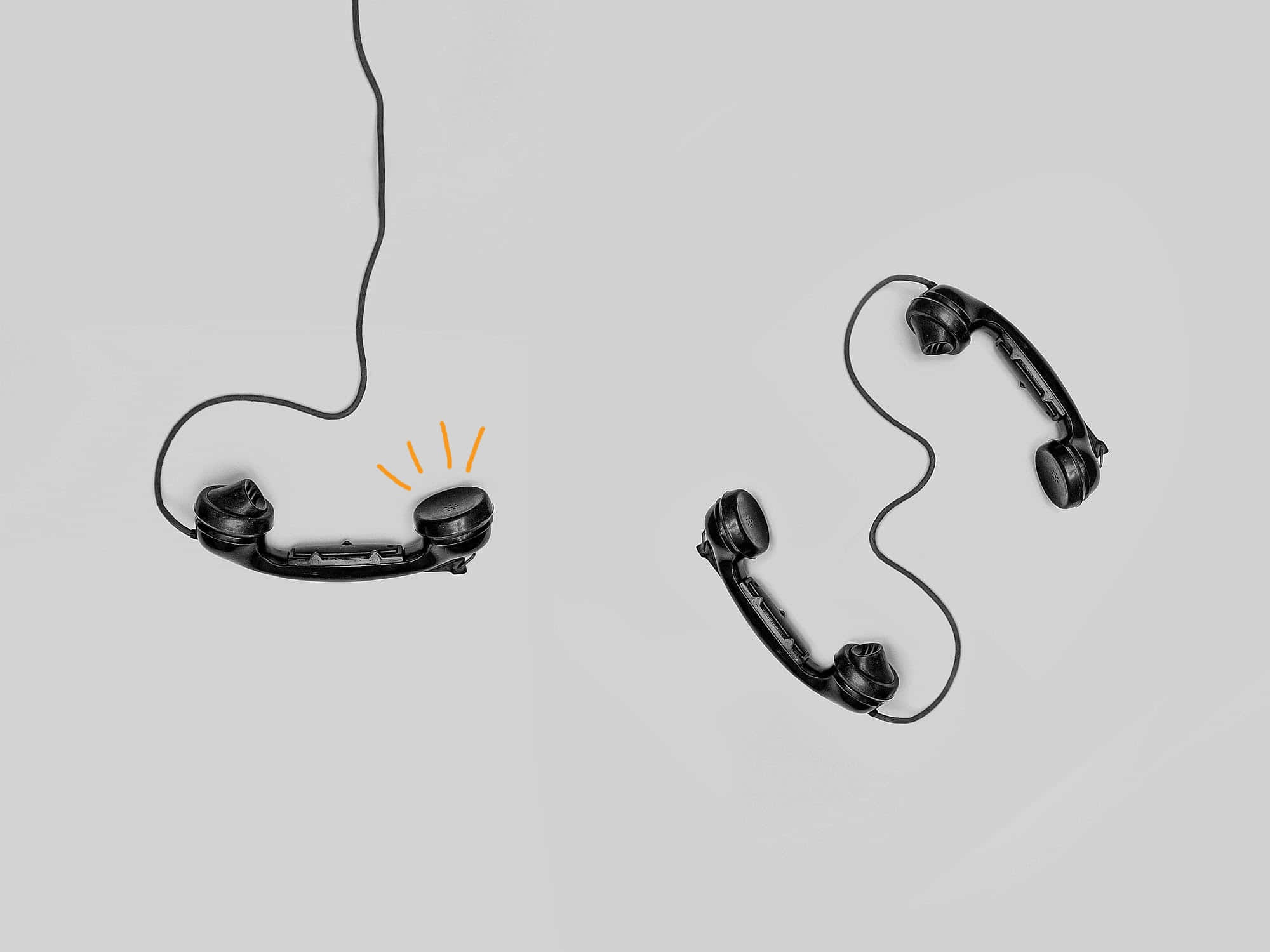 Telemarketing 桌布 壁紙 — 兩個黑色轉盤電話聽筒漂浮在淺灰色背景上，其中一個發出橙色火花。