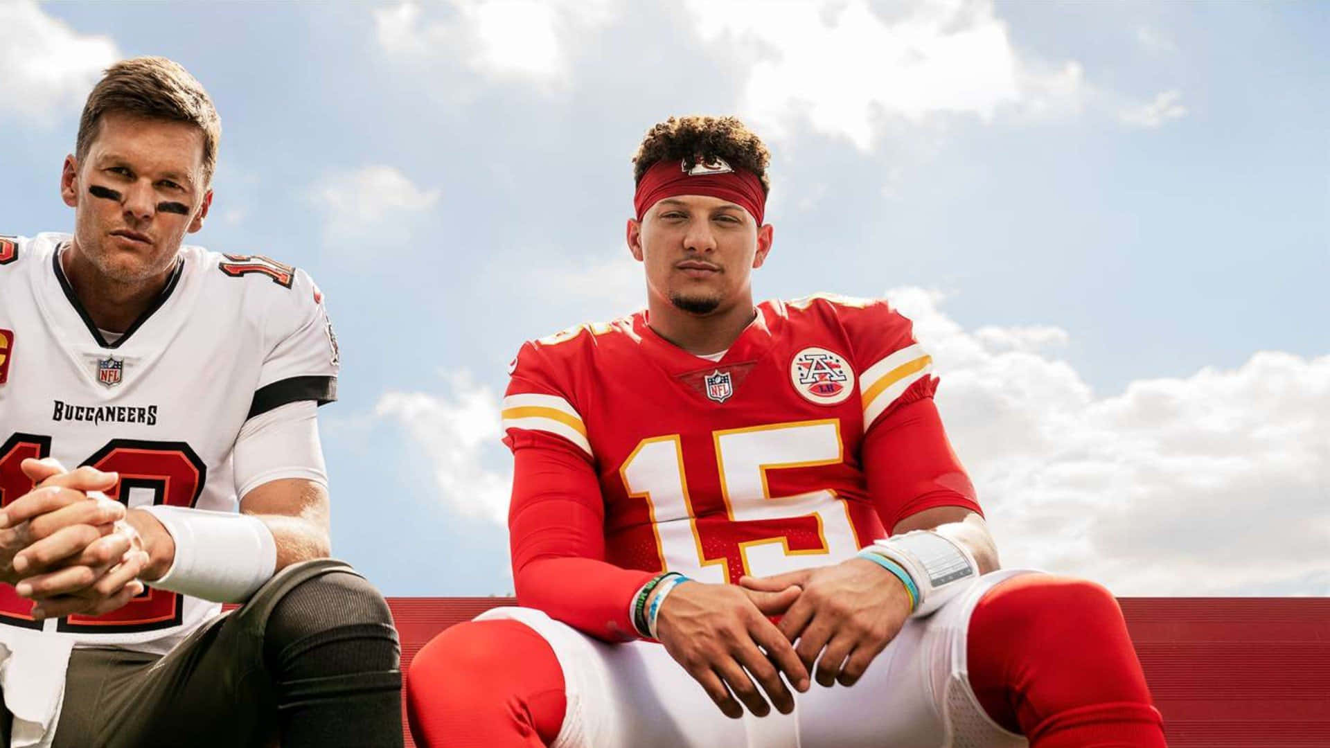 Madden NFL 22 桌布 壁紙 — 兩名NFL四分衛穿著球隊球衣，並排坐在明亮的藍天和蓬鬆的白雲背景下。