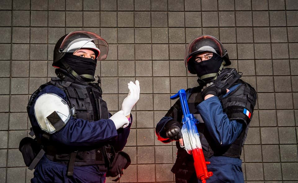 Rainbow Six Siege Rook 桌布 壁紙 — 兩名全副裝備的法國防暴警察站在瓷磚牆前，一人做手勢，另一人拿著彩色水槍。