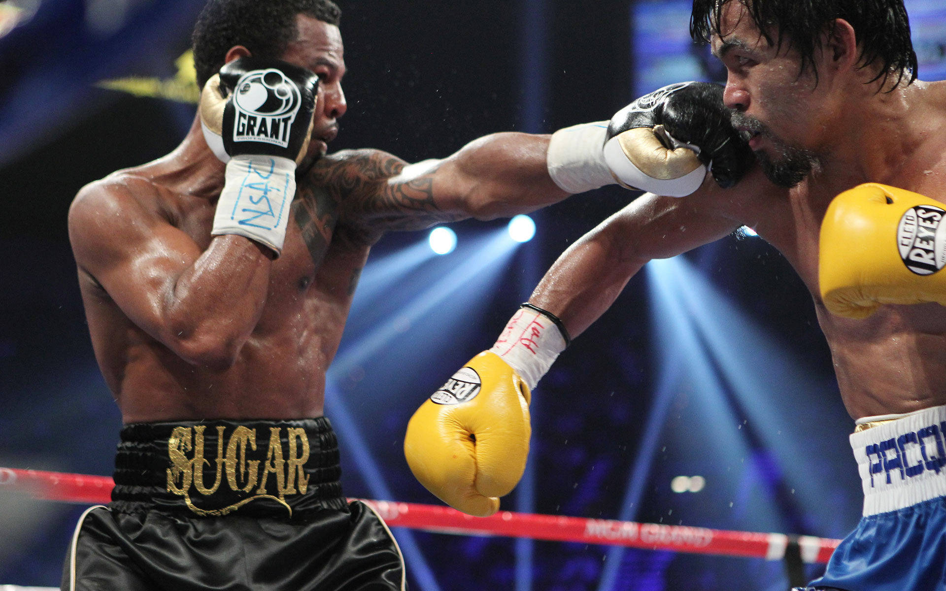 Manny Pacquiao Vs Shane Mosley Fight 壁紙 — 兩名拳擊手在明亮的聚光燈下進行激烈的擂台比賽，汗水在拳擊中飛濺。