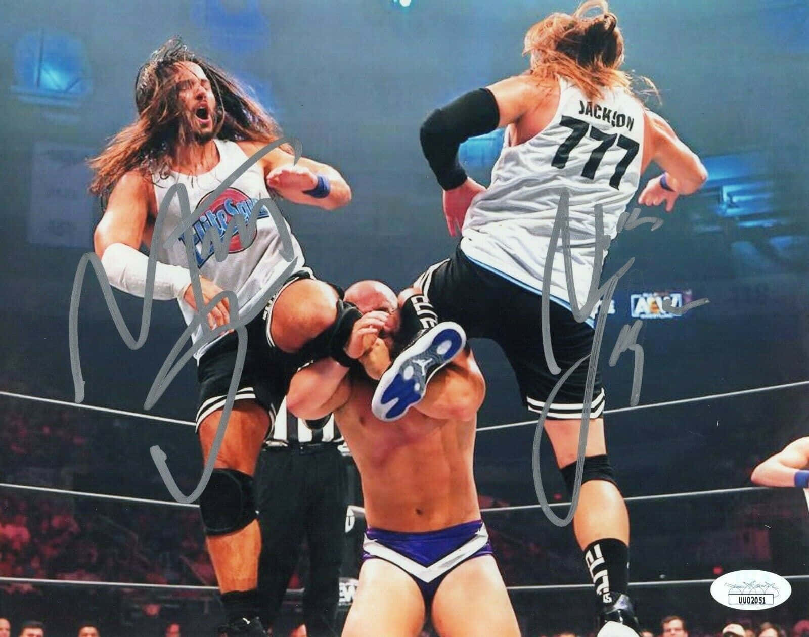 Matt Jackson AEW Fight For The Fallen 壁紙 — 兩名摔角手在半空中對第三名摔角手執行高空飛行動作，場地燈光明亮。
