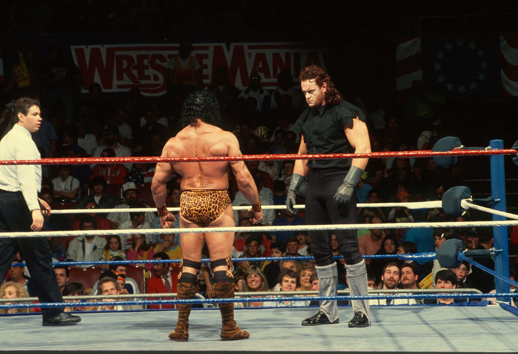 WrestleMania VII 壁紙 — 兩名摔角手在明亮的場館燈光下於擂台上對峙，觀眾專注地觀看。
