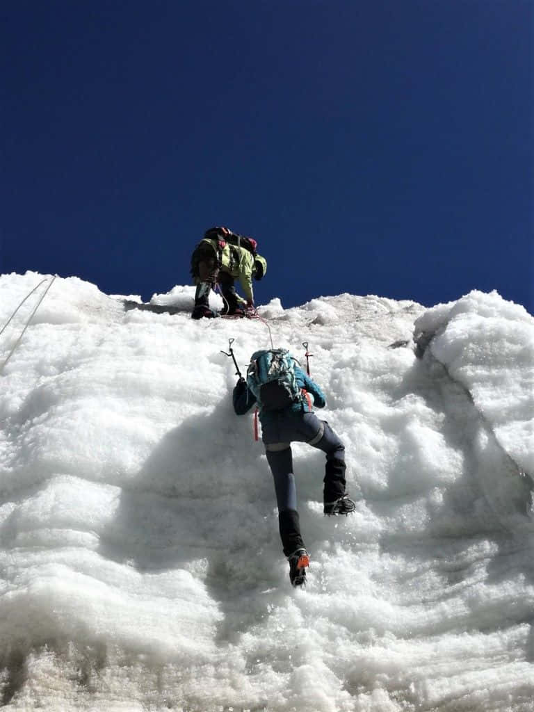 Winter Hiking 桌布 壁紙 — 兩名攀山者在清澈深藍的天空下攀登陡峭的積雪山坡。