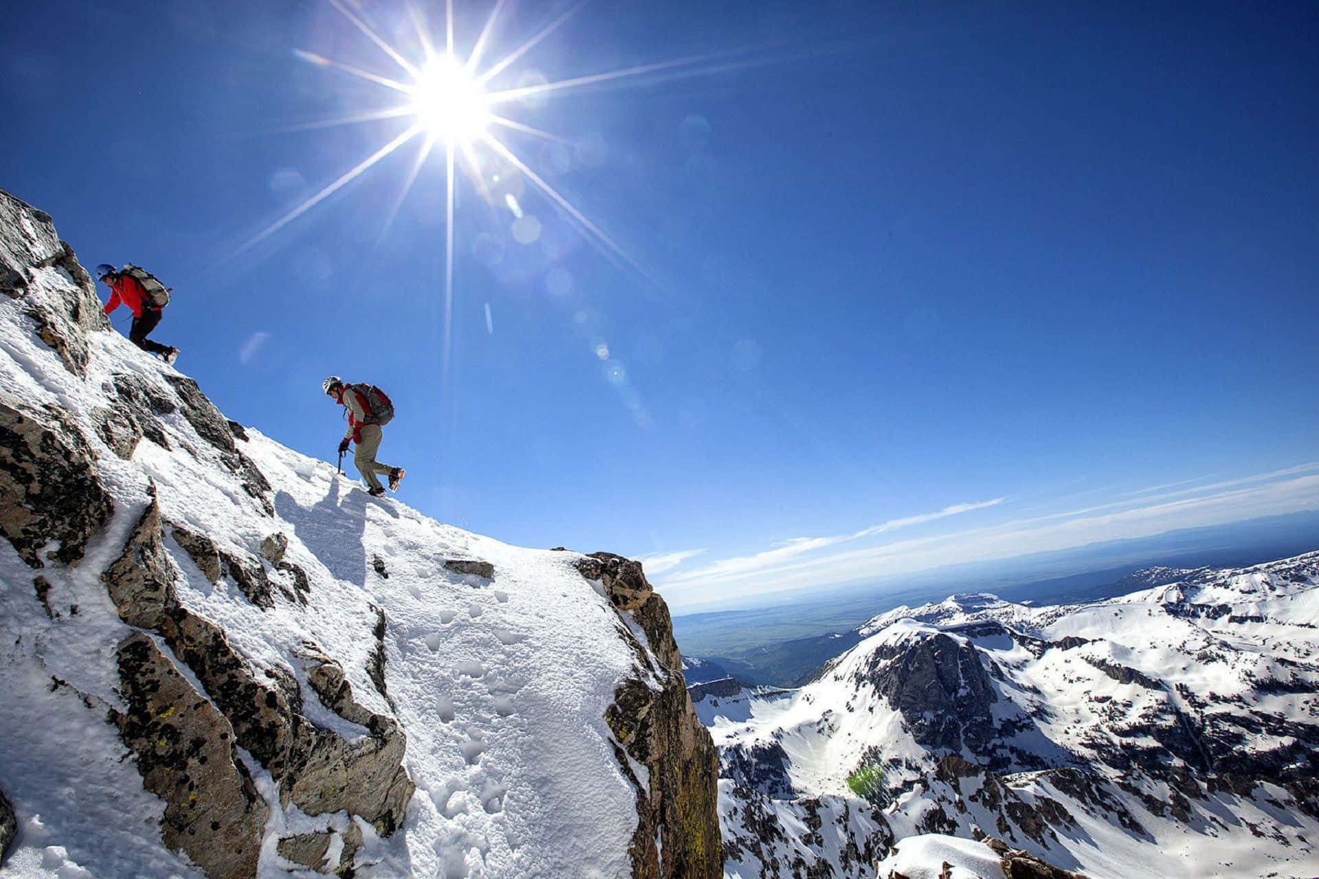 Ice Climbing 桌布 壁紙 — 兩名攀山者在熾熱陽光下攀登積雪山脊，下方是全景視野。