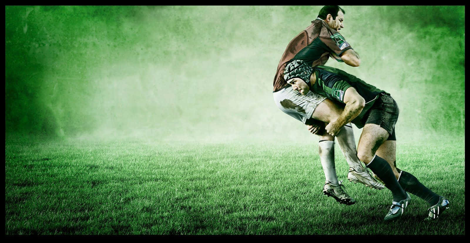Rugby 桌布 壁紙 — 兩名欖球運動員在霧氣瀰漫的綠色球場上，在戲劇性的燈光下激烈纏鬥。