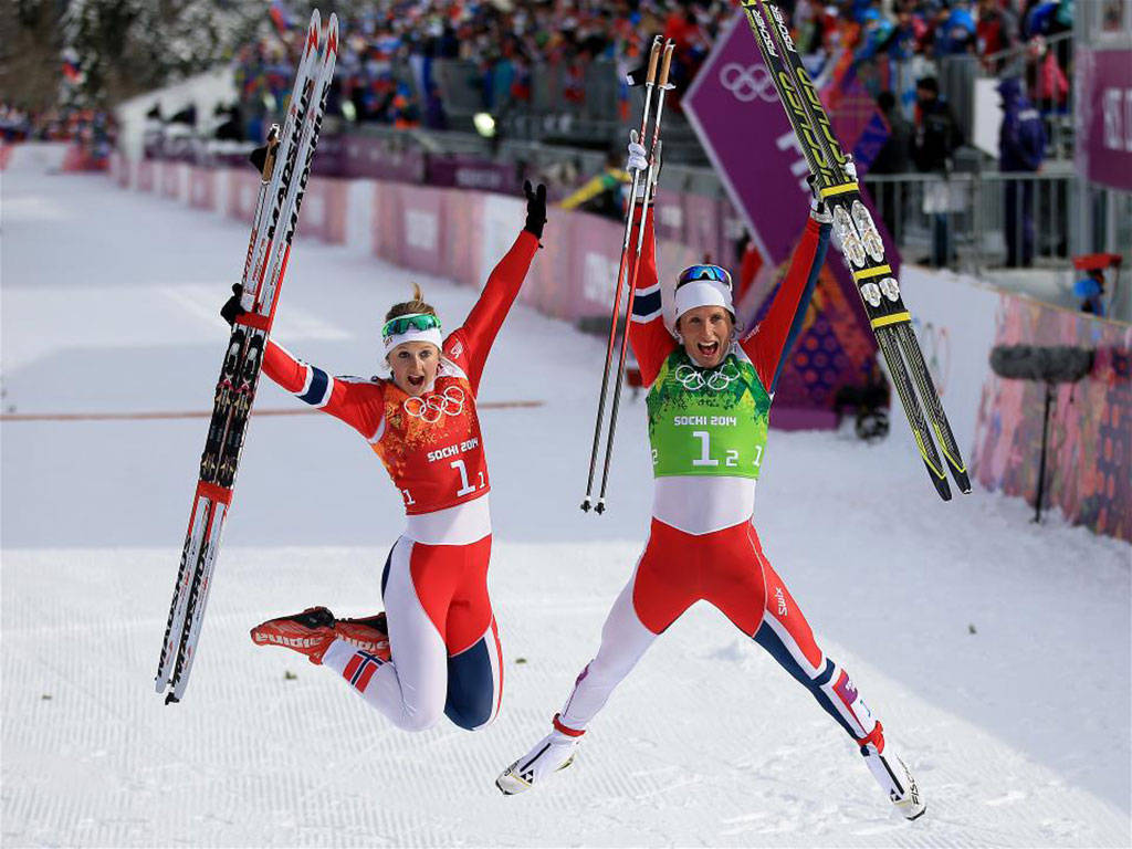 Ski Players At 2014 Winter Olympics 壁紙 — 兩名歡樂的女子越野滑雪運動員在2014年索契冬奧會上高舉滑雪板勝利跳躍。