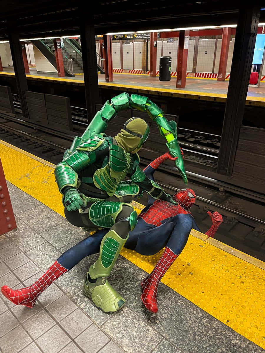 The Scorpion 桌布 壁紙 — 兩名穿著綠色裝甲蠍子和紅色蜘蛛服的cosplayer在地鐵月台上戲劇性地擺姿勢。