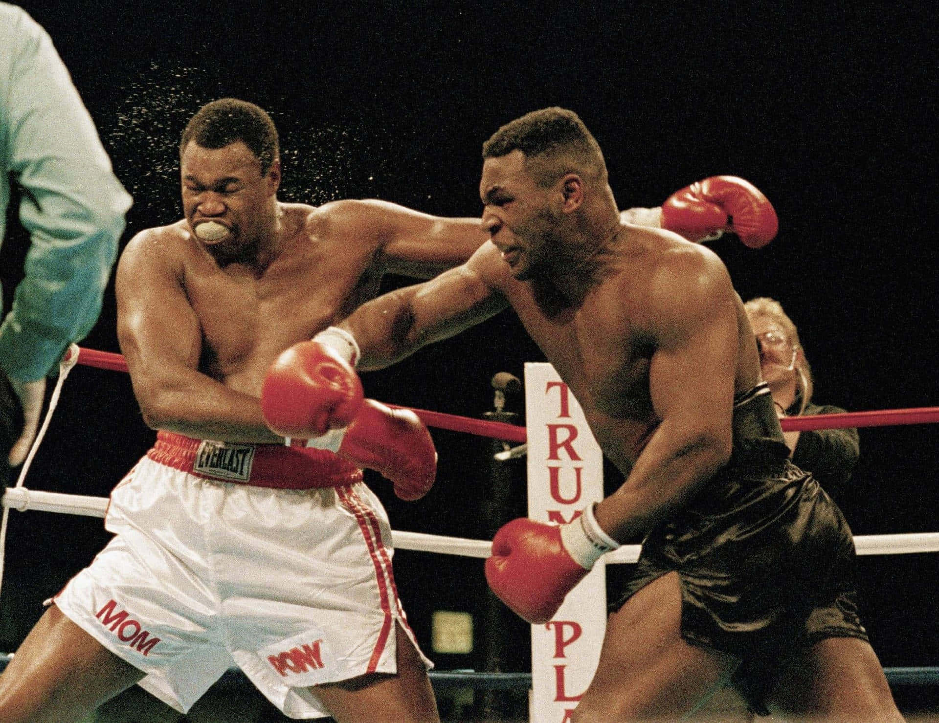 mike tyson 桌布 壁紙 — 兩名肌肉發達的拳擊手在擂台上交鋒，一人出拳命中，另一人痛苦扭曲，汗水飛濺
