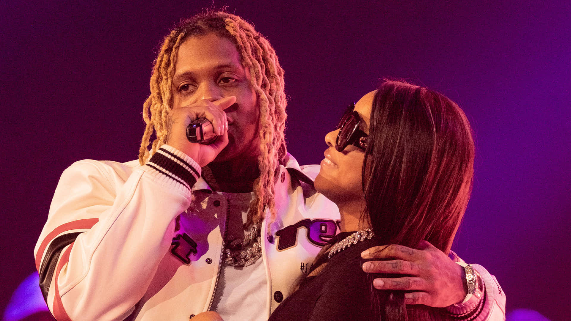 lil durk 桌布 壁紙 — 兩名表演者在紫色燈光下的舞台上，一人手持咪高峰，另一人戴著太陽眼鏡微笑。