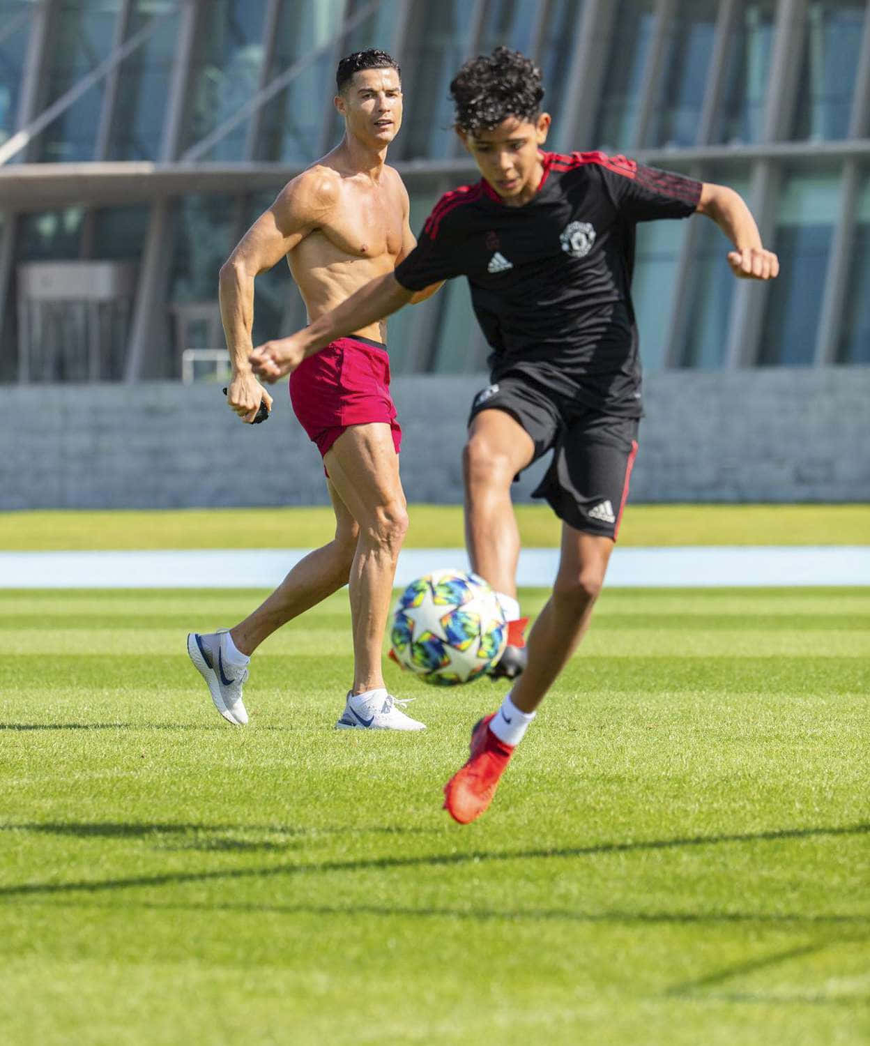 Cristiano Ronaldo 桌布 壁紙 — 兩名足球運動員在明亮的日光下，於充滿活力的綠色球場上激烈爭奪一個色彩繽紛的球。