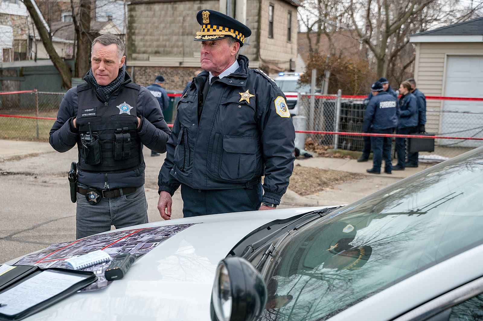 John C. Mcginley 桌布 壁紙 — 兩名身穿制服的警察站在一輛白色汽車附近，背景有紅色封鎖帶和光禿禿的樹木的犯罪現場。
