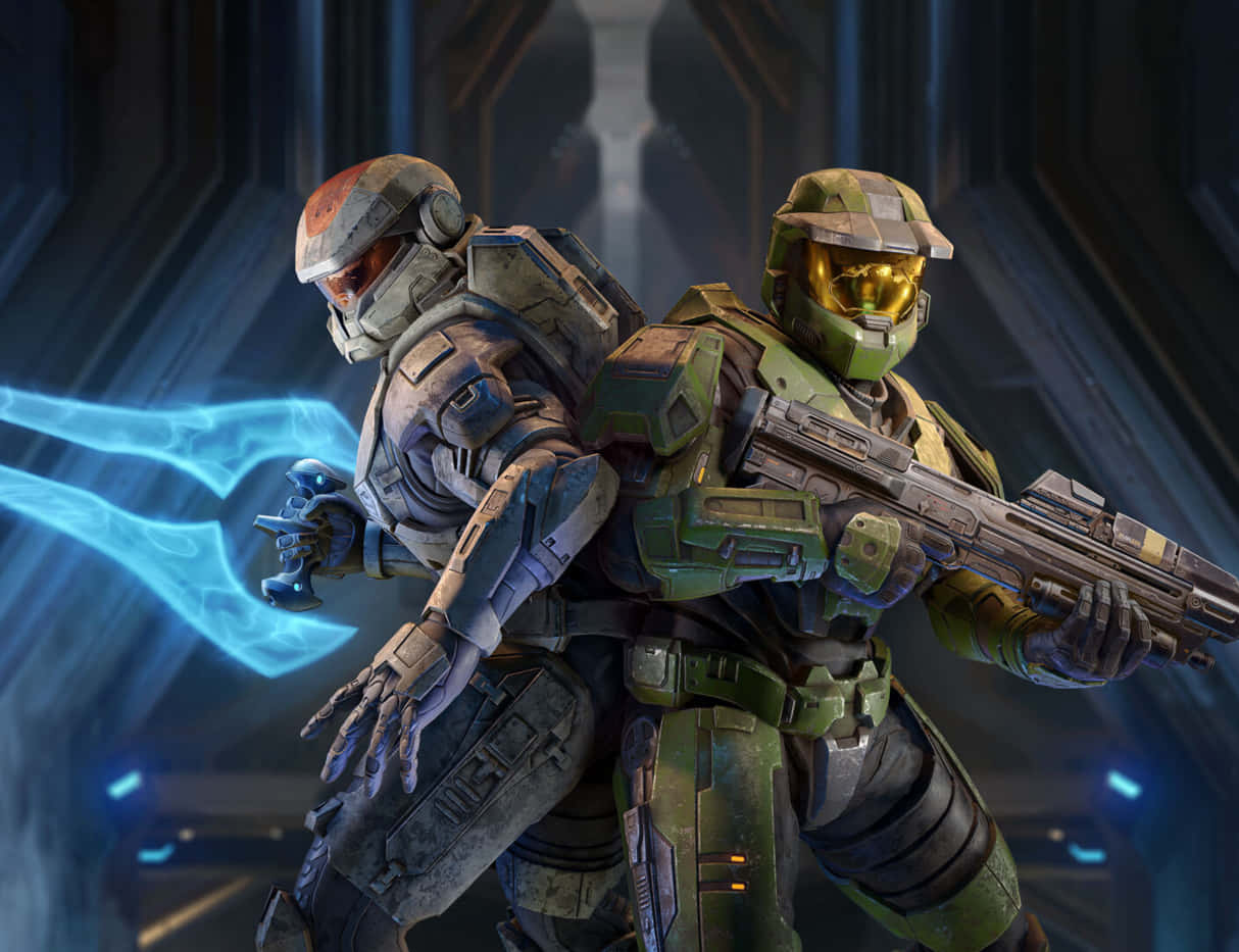 Halo Spartans 桌布 壁紙 — 兩名身穿未來裝備的裝甲士兵在昏暗的科幻走廊中準備就緒，其中一人揮舞著發光的藍色能量劍。