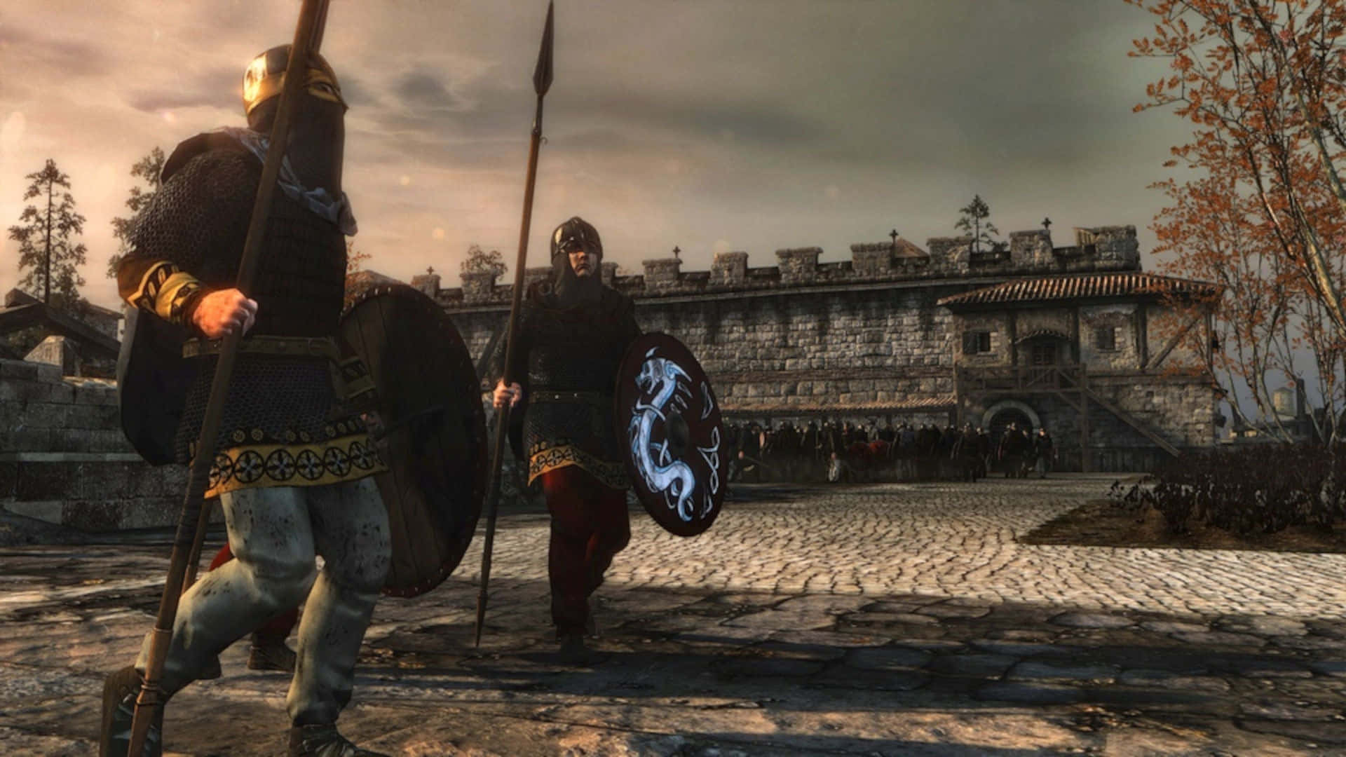 全軍破敵：阿提拉 桌布 壁紙 — 兩名身穿盔甲的中世紀戰士，在陰天下一座石城堡前的鵝卵石路上，手持長矛和盾牌向前行進。