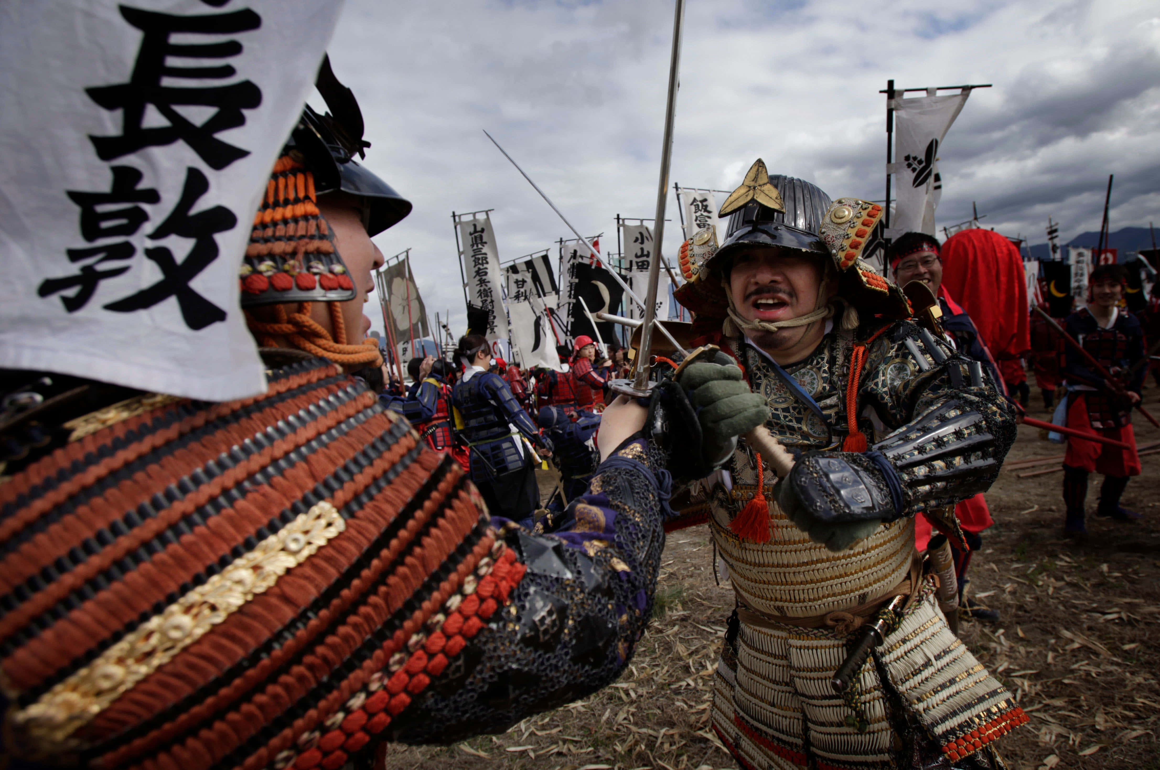 Samurai Battle 桌布 壁紙 — 兩名身穿華麗鎧甲的武士在陰天下一場戲劇性的重演中刀劍交鋒。