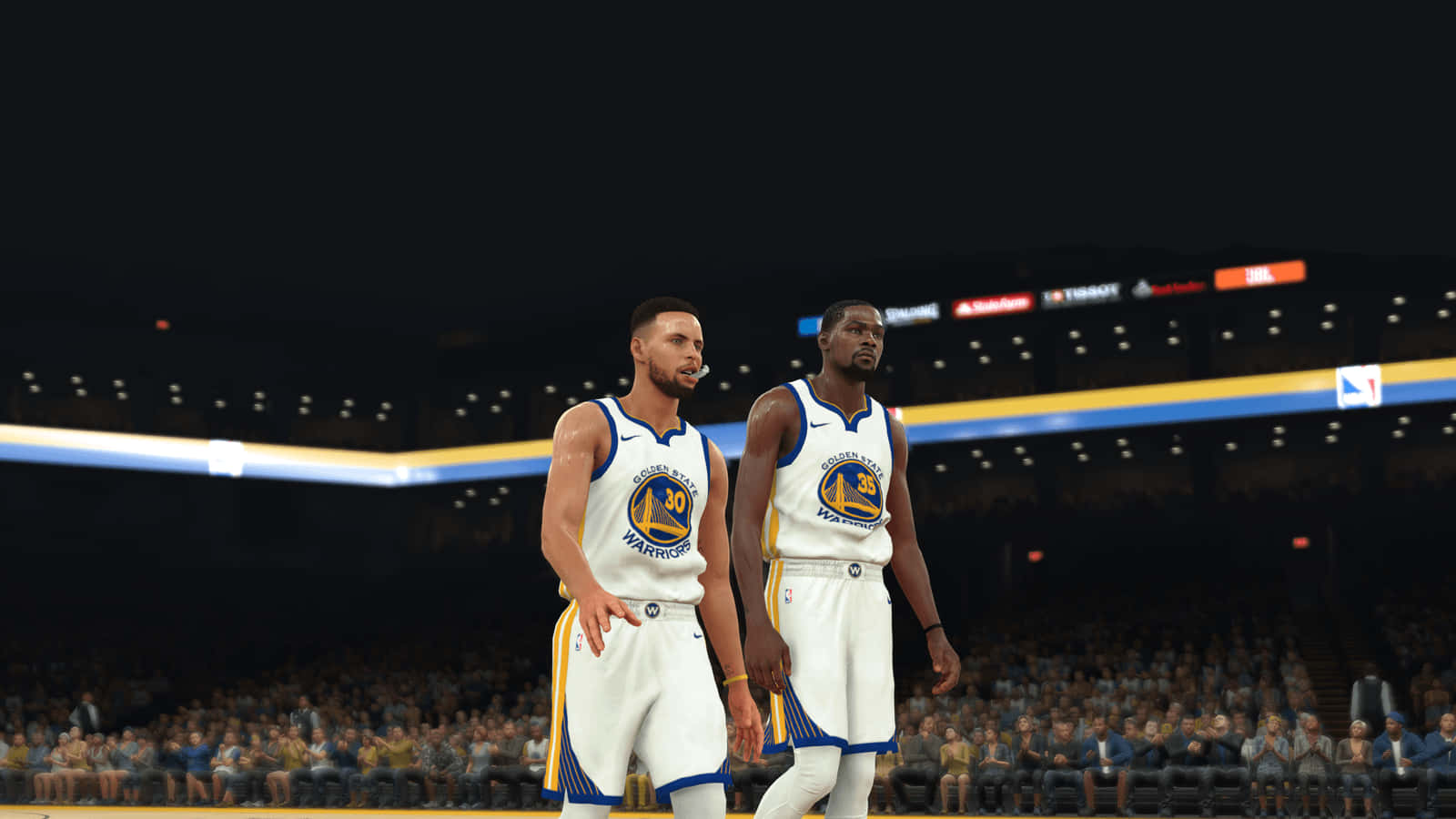 NBA 2K20 GSW 壁紙 — 兩名身穿金州勇士隊球衣的籃球運動員站在燈火通明的球場上，背景是座無虛席的觀眾。