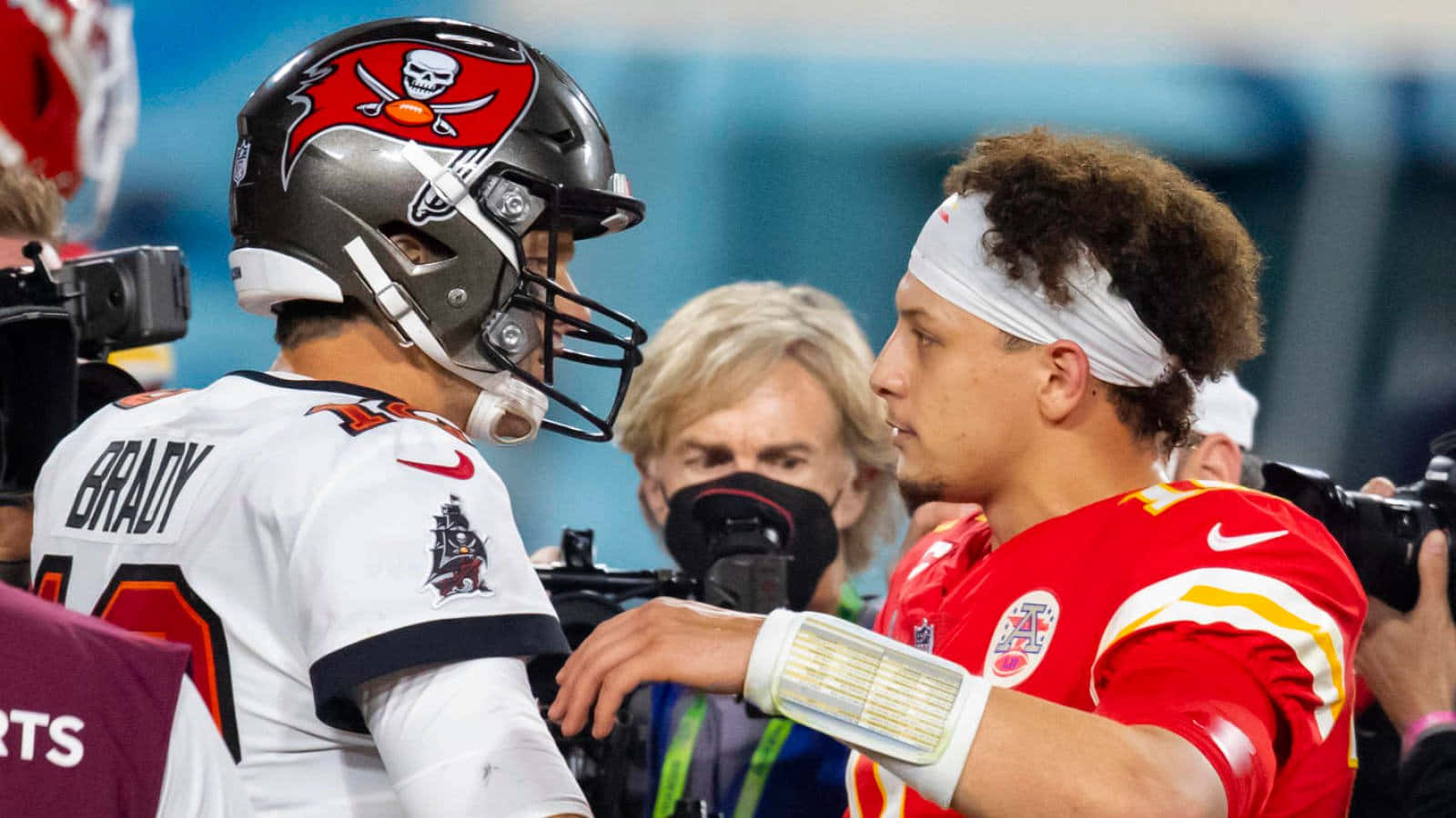 Madden NFL 22 桌布 壁紙 — 兩名身穿頭盔和球衣的NFL四分衛在比賽中對峙，周圍有攝像機和記者。
