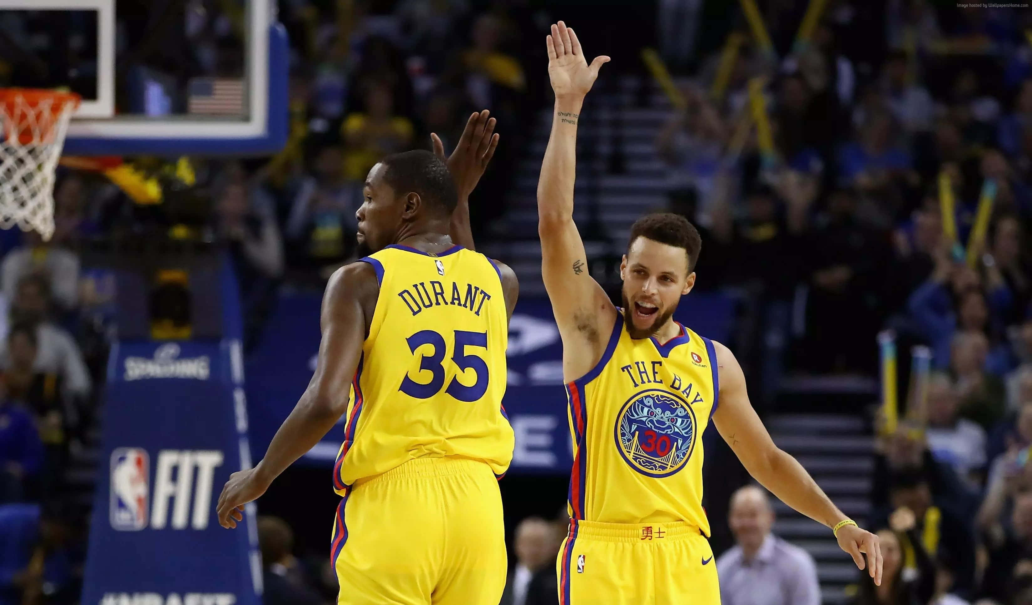 steph curry 桌布 壁紙 — 兩名身穿黃色球衣的籃球運動員在明亮的場館燈光下擊掌慶祝一次進攻。