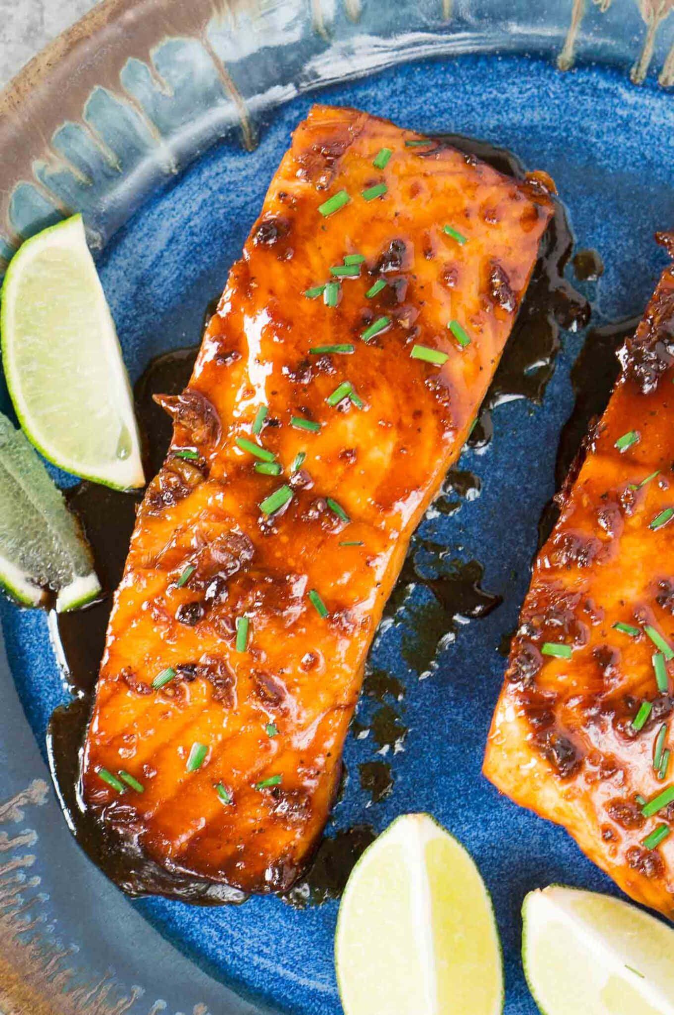 Salmon 桌布 壁紙 — 兩塊釉面三文魚柳，飾以細香蔥和青檸角，放在有紋理的藍色陶瓷碟上。