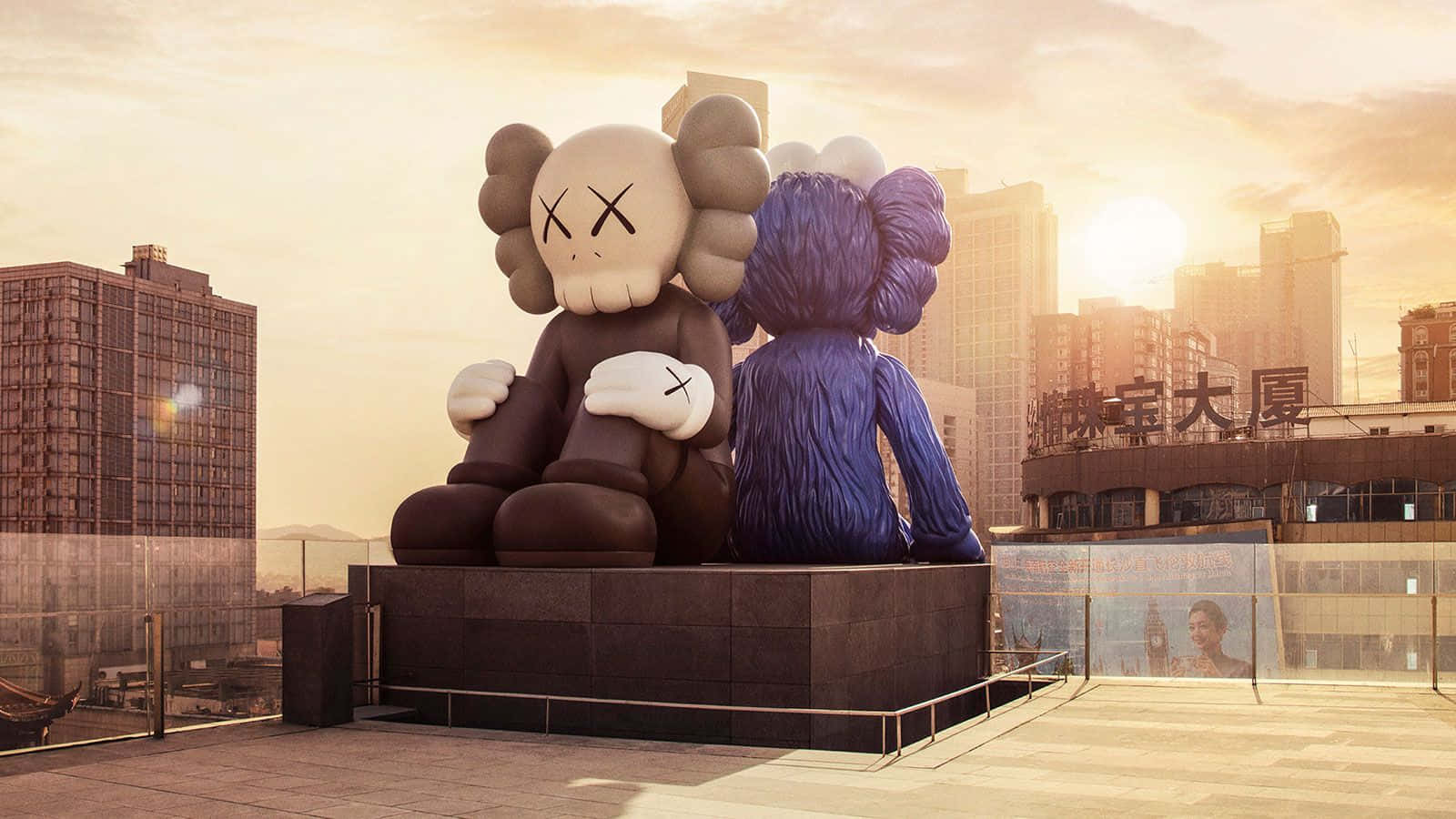 Kaws Bff 桌布 壁紙 — 兩尊巨大的KAWS雕塑坐在屋頂上擁抱，背景是現代城市天際線上的金色日落。