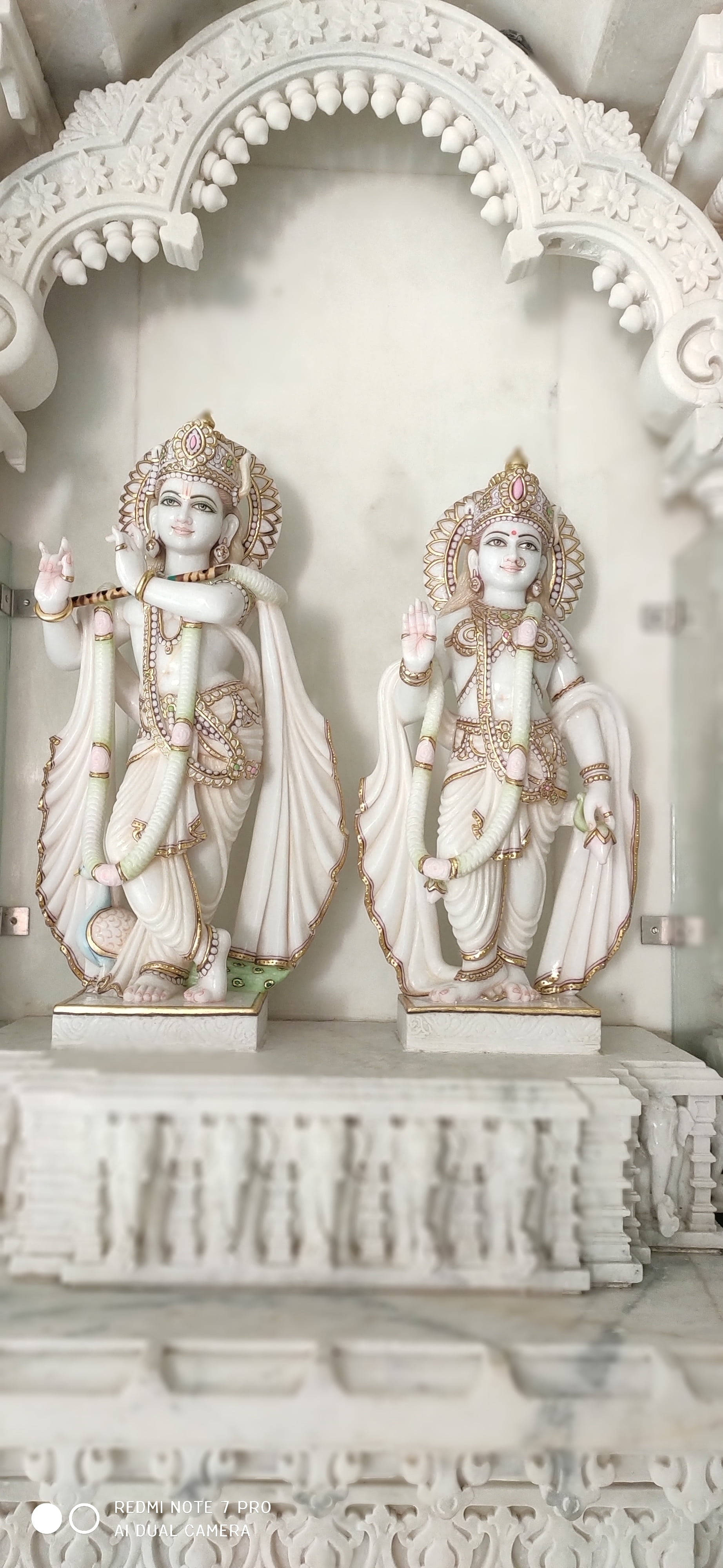 krishna 3d 桌布 壁紙 — 兩尊雕刻精美的印度教神祇白色大理石雕像，優雅地矗立在華麗的拱形壁龕下。