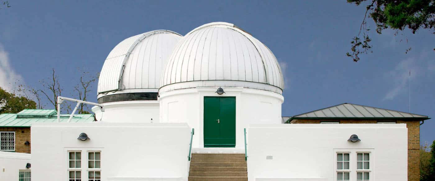 Observatory 桌布 壁紙 — 兩座白色圓頂天文台，帶有綠色門，矗立在晴朗的藍天下，周圍環繞著樹木。