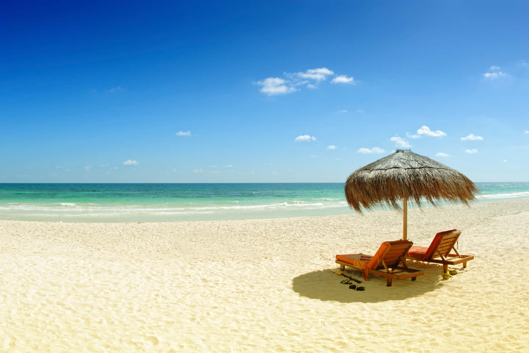 Mexican Beach 桌布 壁紙 — 兩張木製躺椅在茅草傘下，位於純淨白色沙灘上，伴隨碧綠海洋和清澈藍天。