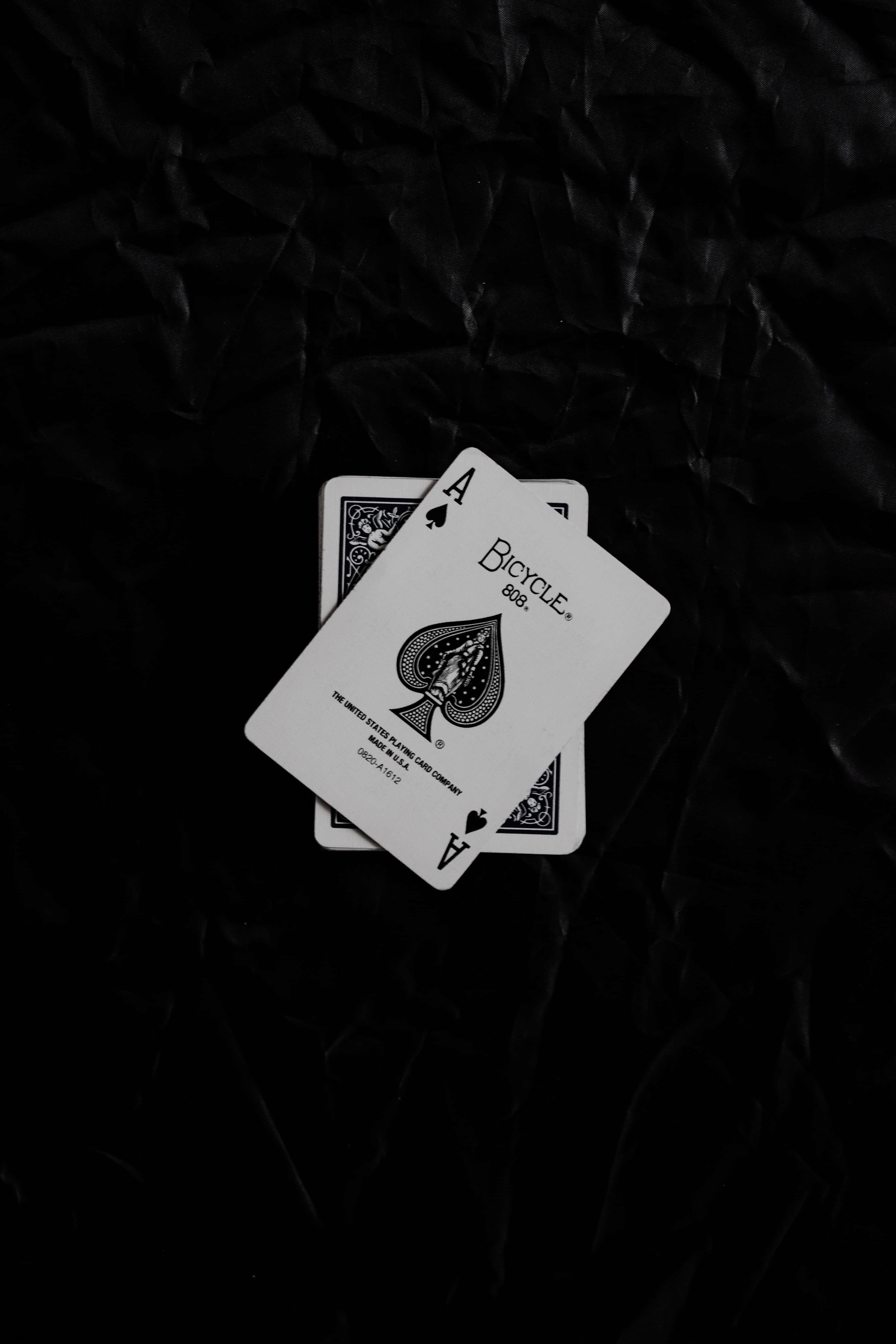 Playing Cards 桌布 壁紙 — 兩張白色Bicycle Ace of Spades啤牌放在皺巴巴的黑色紙背景上。