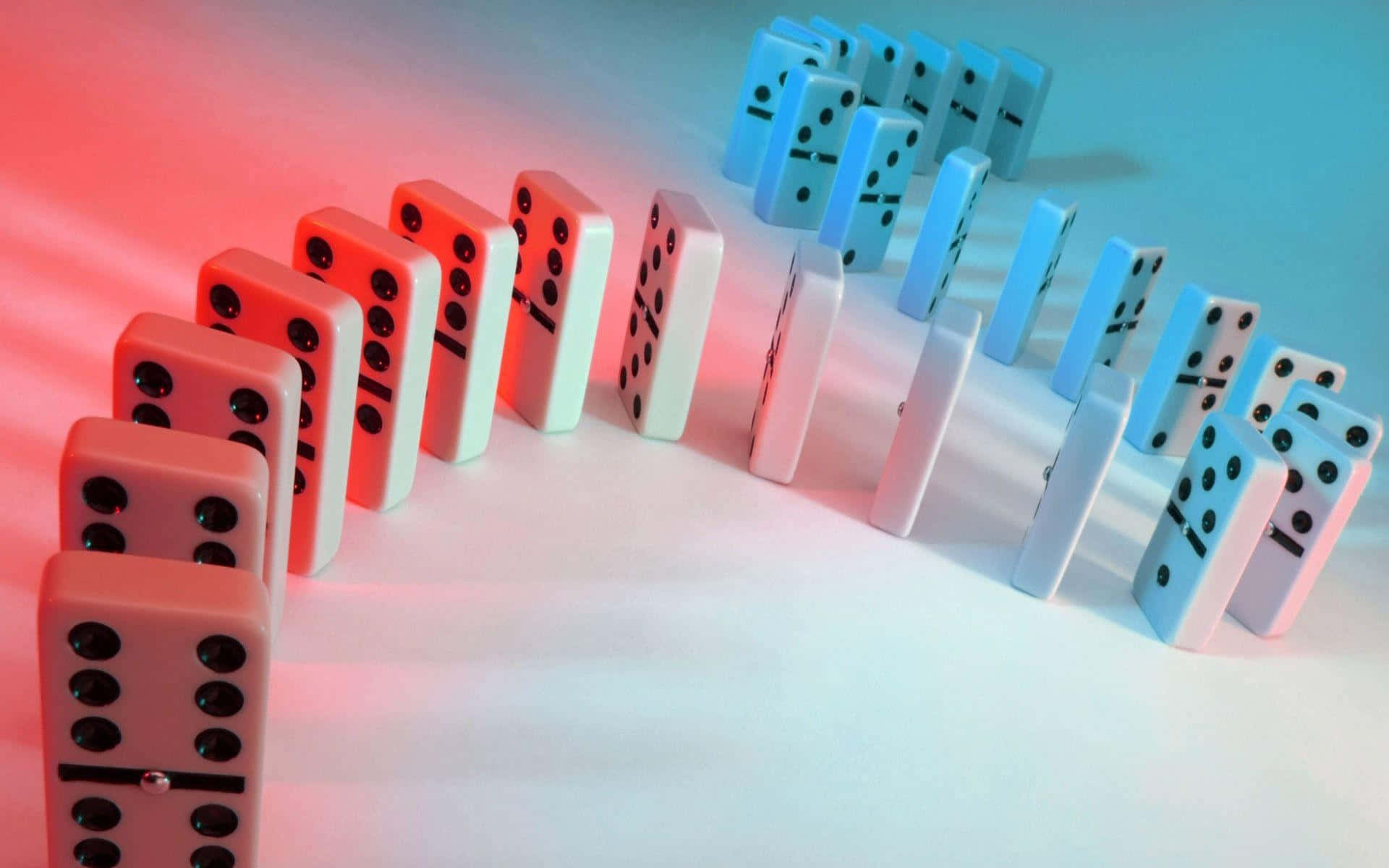 Domino 桌布 壁紙 — 兩排相對的骨牌在戲劇性的紅藍燈光下準備倒下。