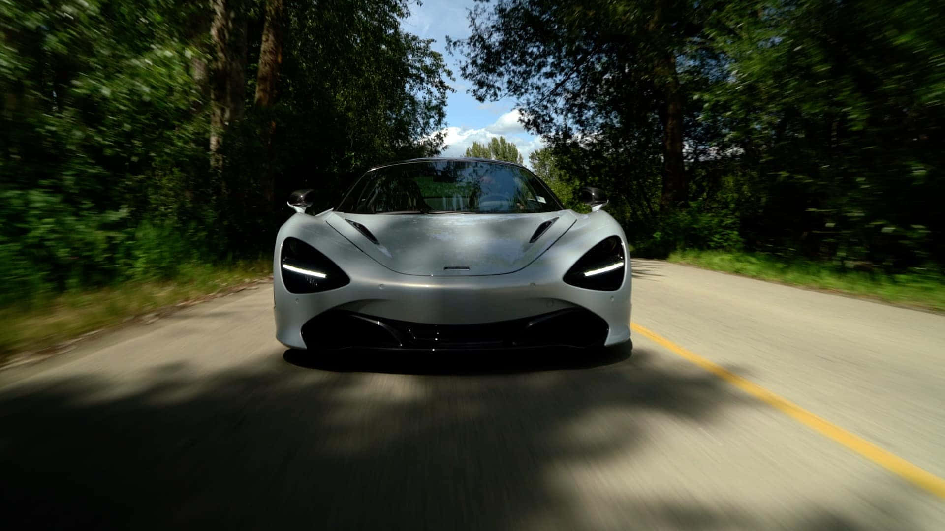 銀色McLaren在森林道路上高速行駛，帶有動態模糊效果。