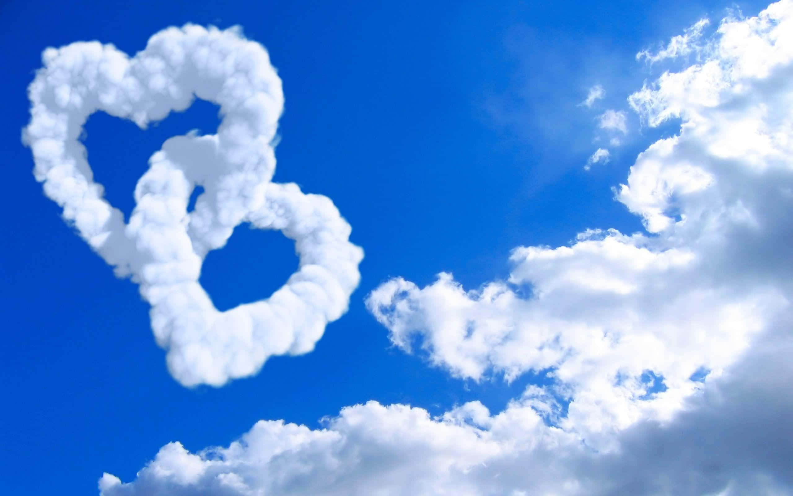 Beautiful Love 桌布 壁紙 — 兩朵蓬鬆白色心形雲朵漂浮在充滿活力的藍天上，點綴著縷縷薄雲。