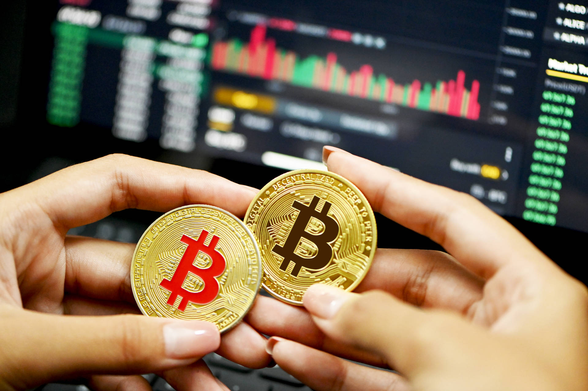 兩枚金色比特幣握在手中，後面有交易屏幕。