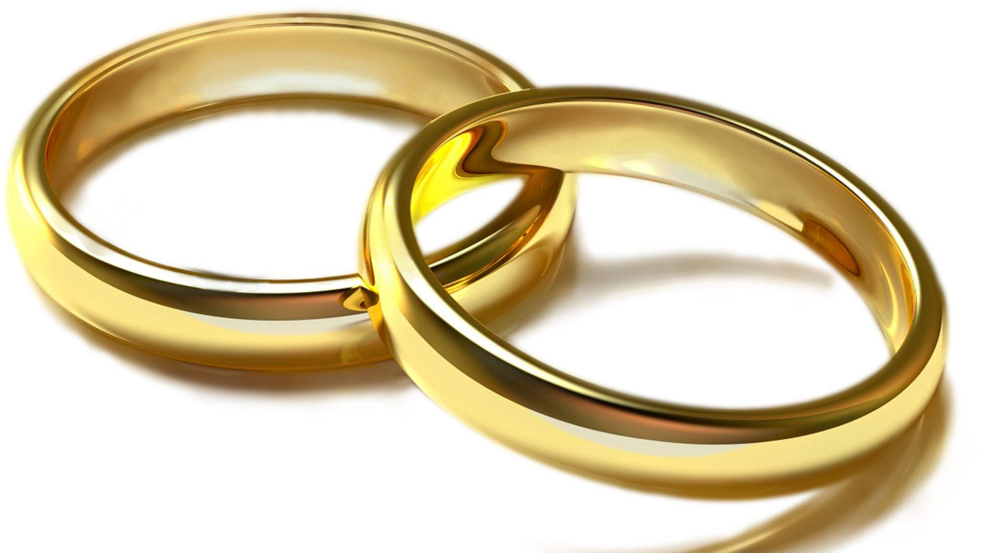 兩枚金質婚戒 壁紙 — 兩枚閃閃發光的金色結婚戒指在純白背景上交織，帶有柔和陰影。