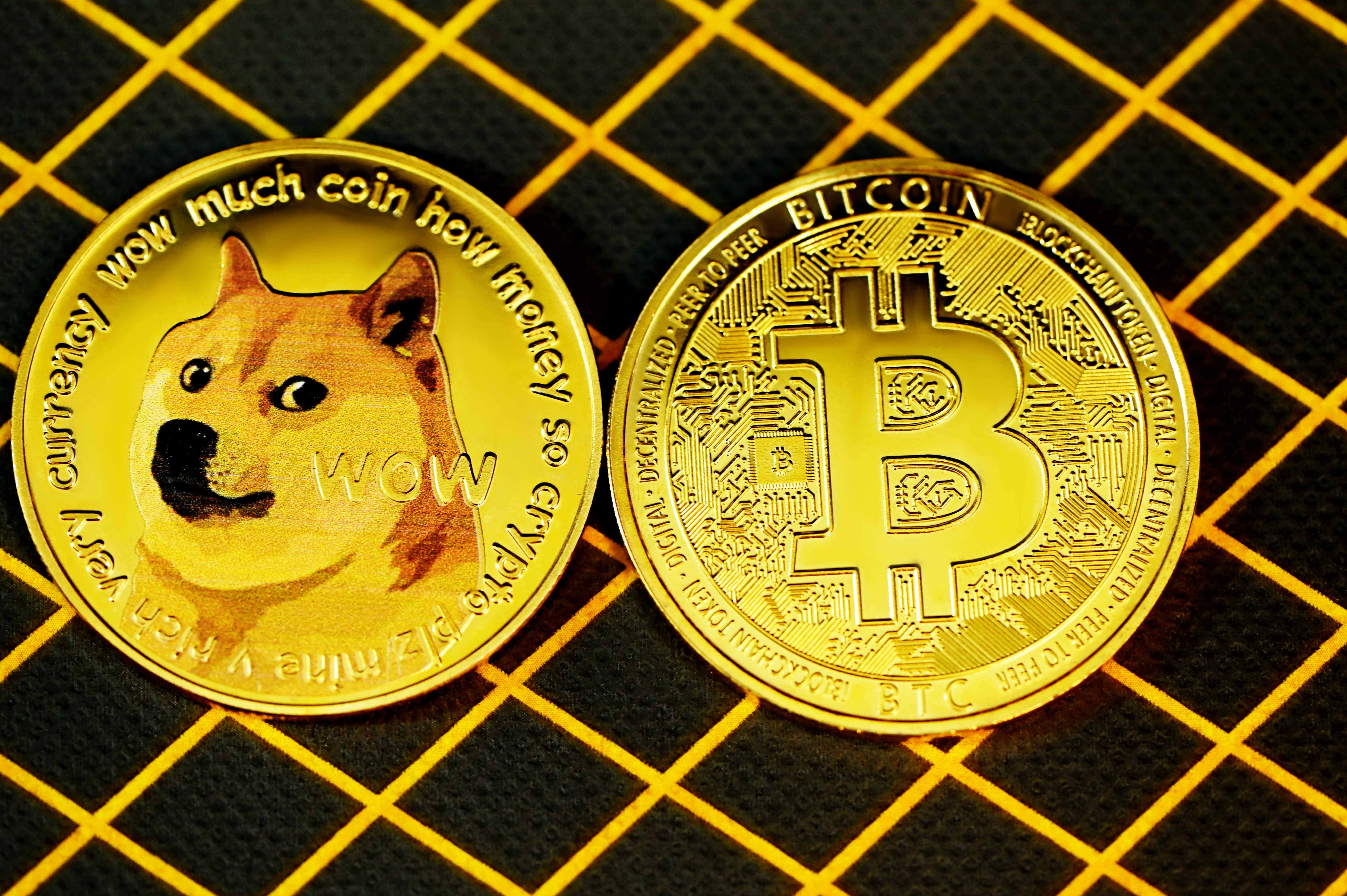 Dogecoin 桌布 壁紙 — 兩枚閃亮的金幣，上面有狗狗幣的柴犬和比特幣的「B」標誌，放在帶有黃色線條的黑色網格上。