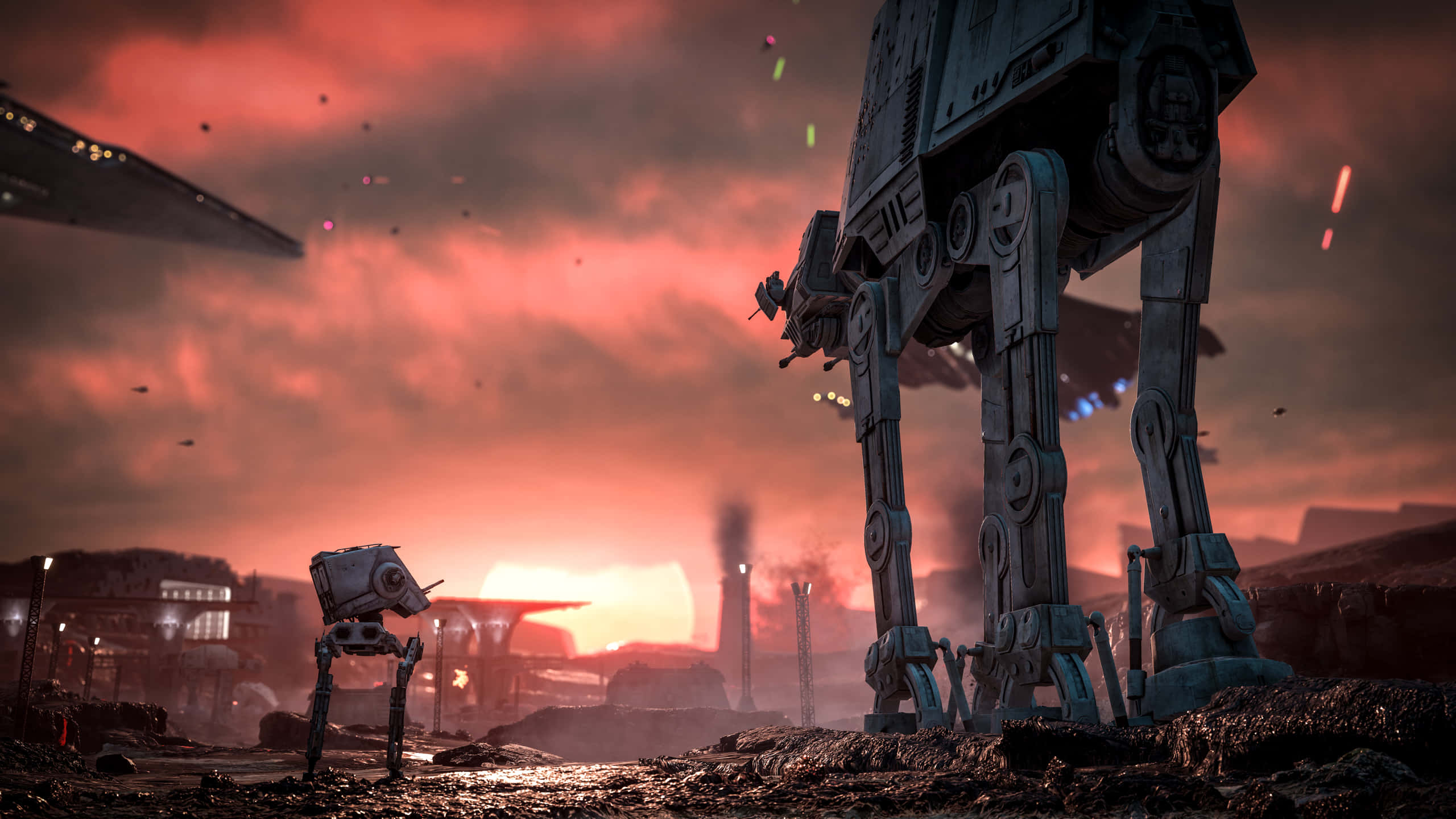 Star Wars Games 桌布 壁紙 — 兩架AT-AT步行機佇立喺荒涼嘅戰場上，天空係火紅嘅日落，遠處有船隻同煙霧。