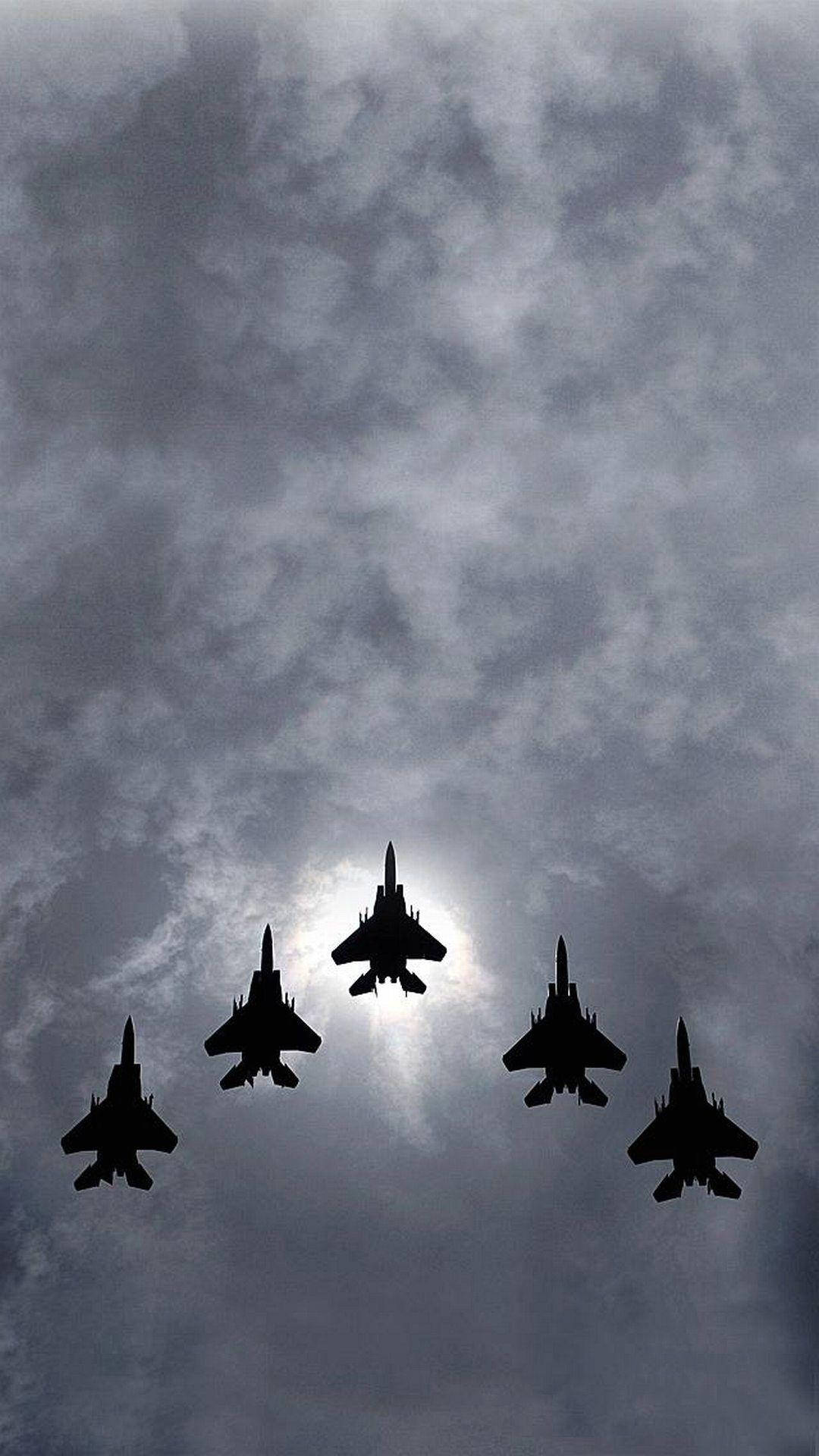 五架戰鬥機在多雲天空中編隊飛行，太陽在身後。