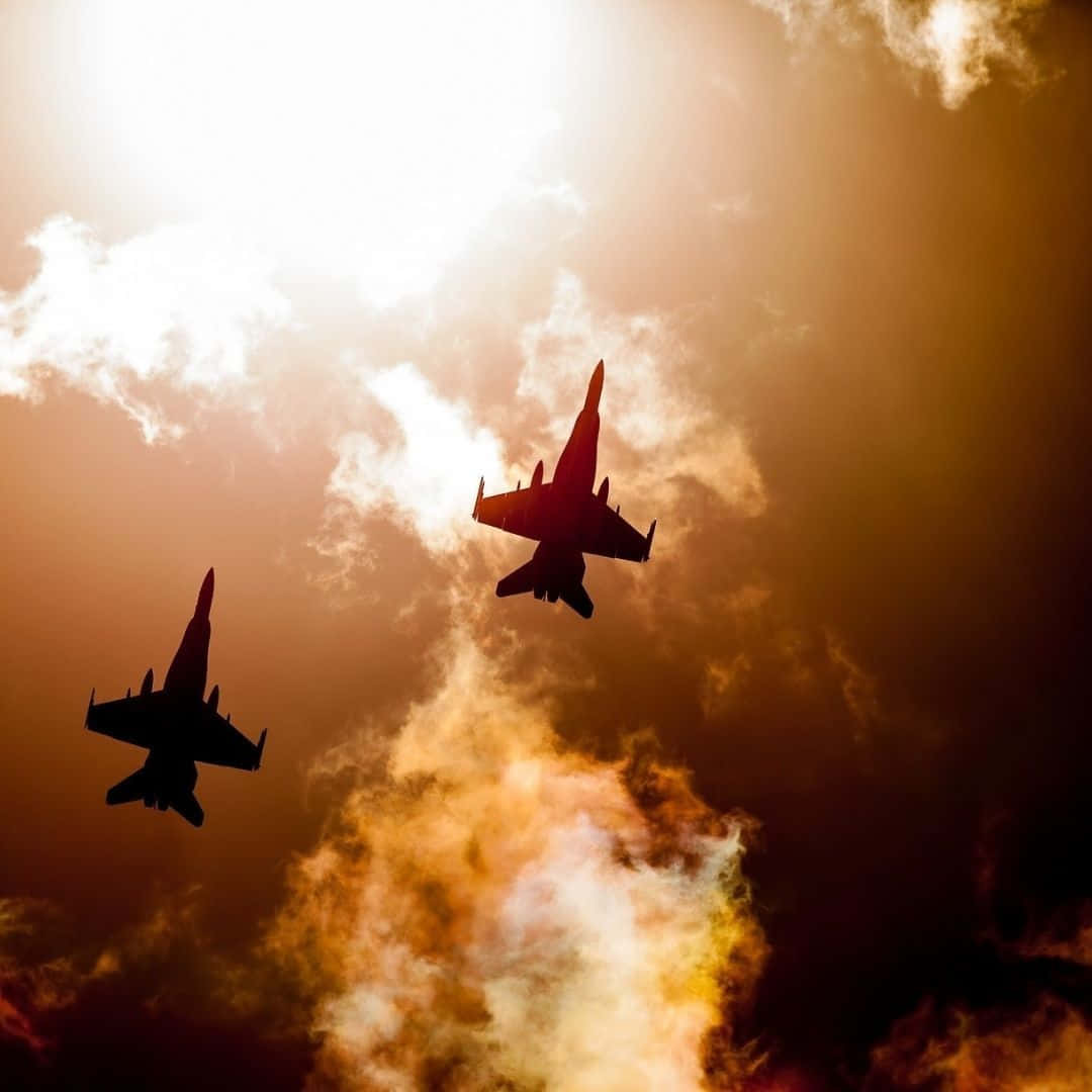 Air Force 桌布 壁紙 — 兩架戰鬥機以剪影姿態翱翔，背景是帶有戲劇性雲彩的熾熱日落天空。