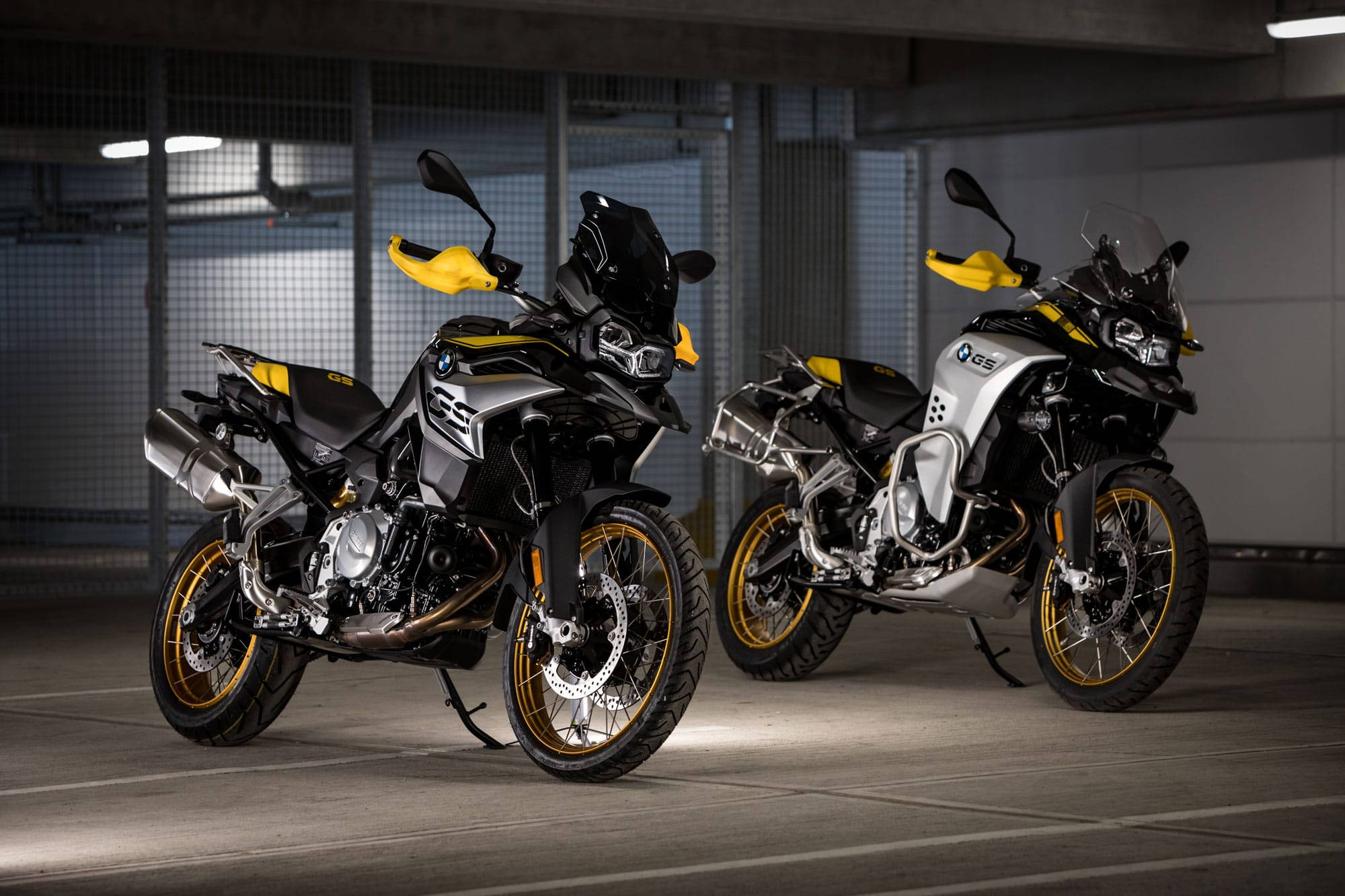 Bmw 桌布 壁紙 — 兩架時尚的BMW GS冒險電單車，帶有鮮明的黃色點綴，停泊在燈光昏暗的地下停車場。