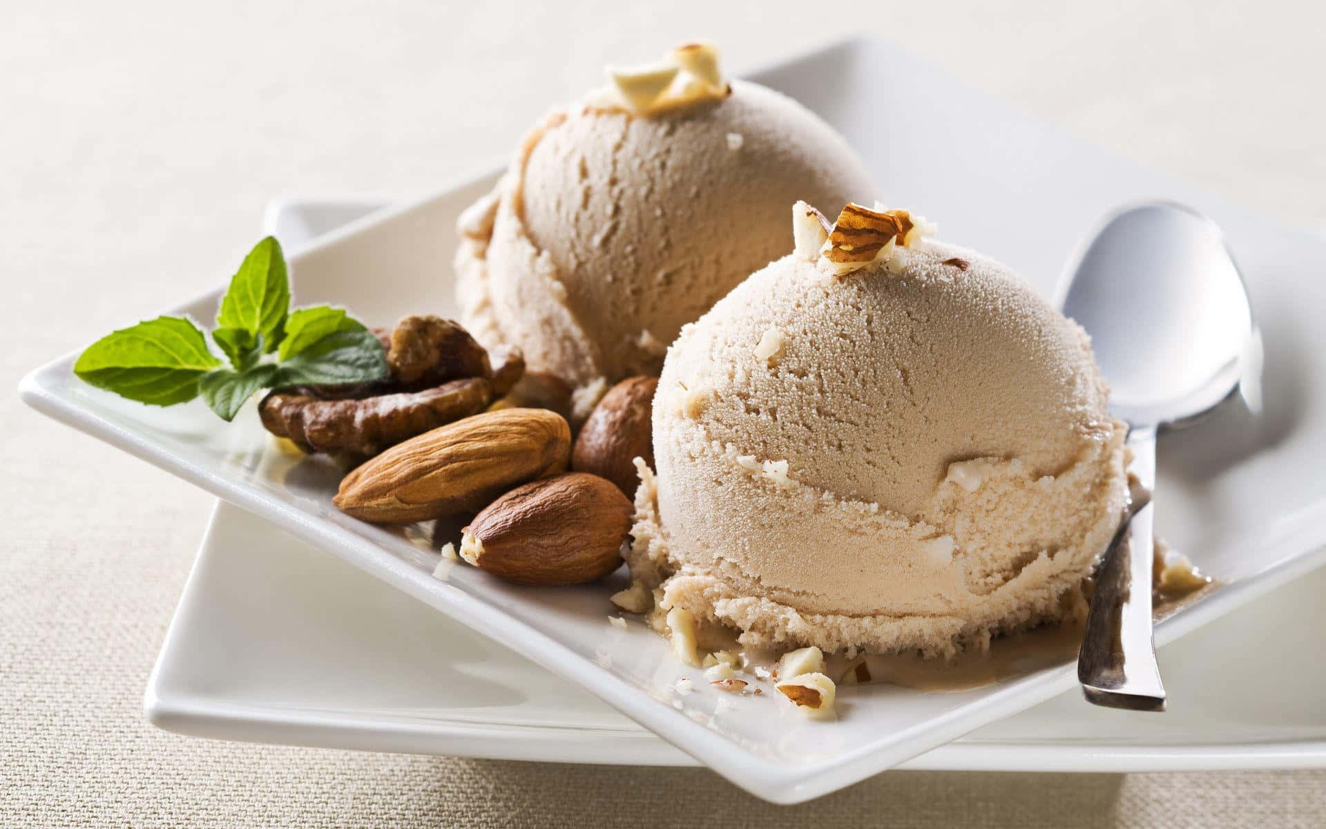 Ice Cream 桌布 壁紙 — 兩球奶油杏仁雪糕，飾以整粒杏仁和薄荷葉，置於白色碟上。