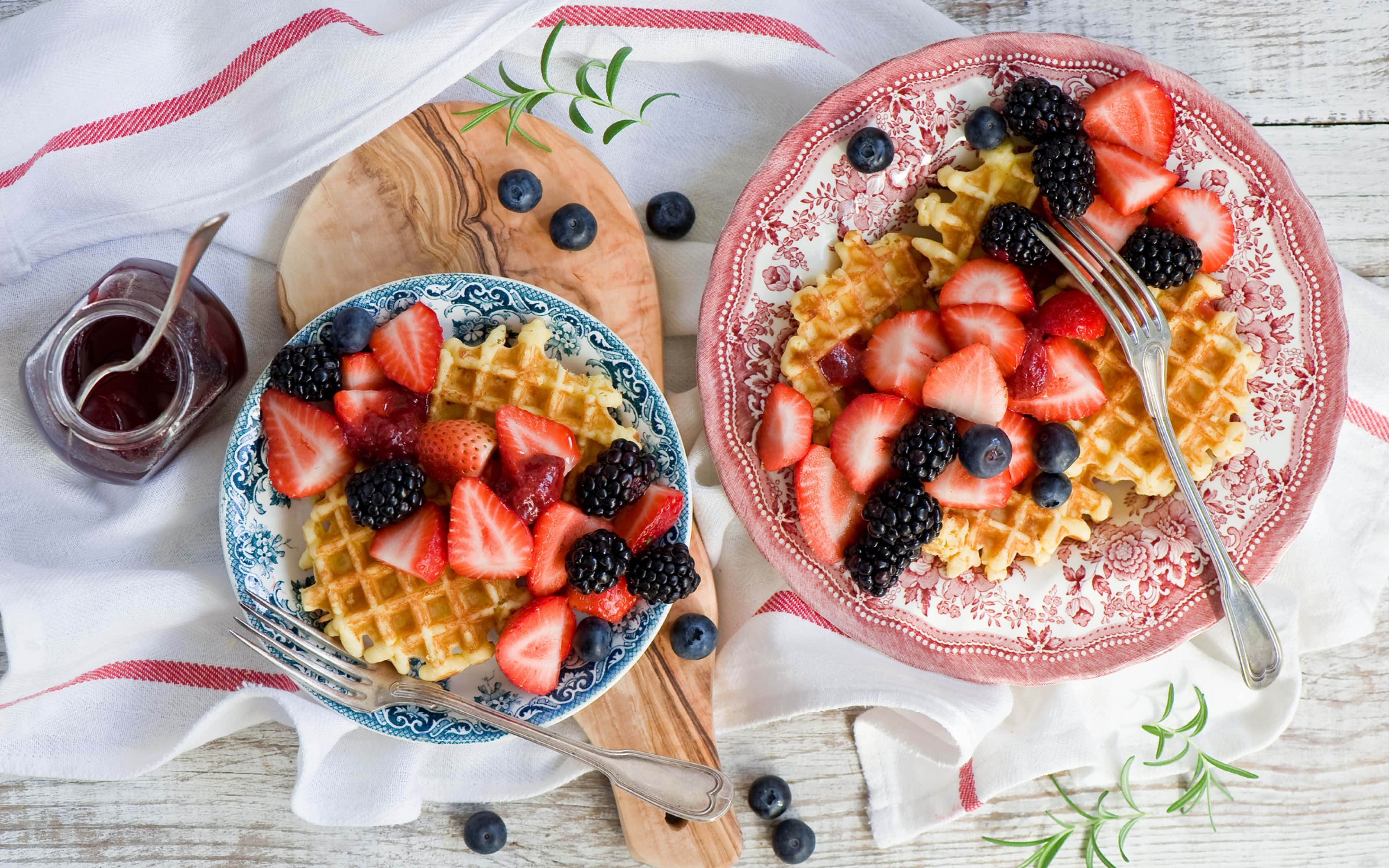 Waffle 桌布 壁紙 — 兩盤金黃色窩夫，上面鋪滿新鮮草莓、黑莓和藍莓，放在質樸的木桌上。