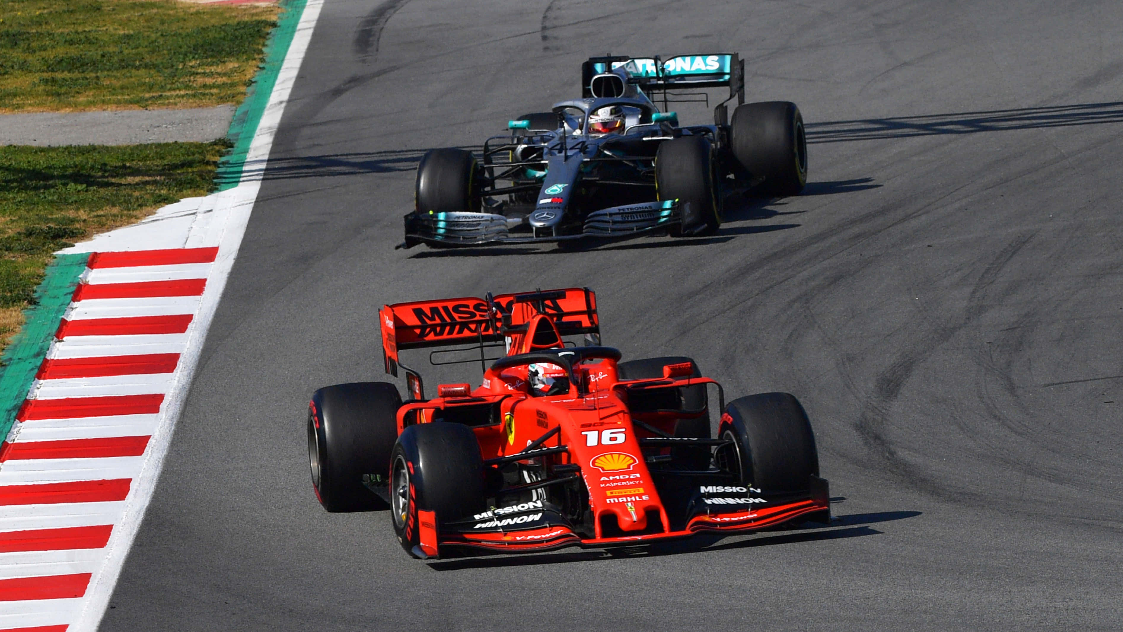 F1 2019 桌布 壁紙 — 兩輛一級方程式賽車在陽光普照的賽道上緊密競賽，賽道設有紅、白、綠色路肩。