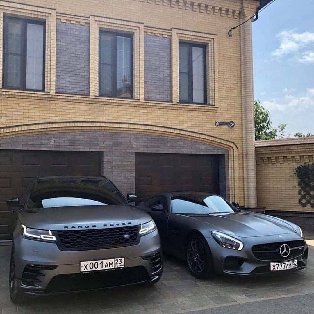 Family Car 桌布 壁紙 — 兩輛啞光灰色豪華車，一輛Range Rover和一輛Mercedes-AMG，停在米色磚砌豪宅車庫前。