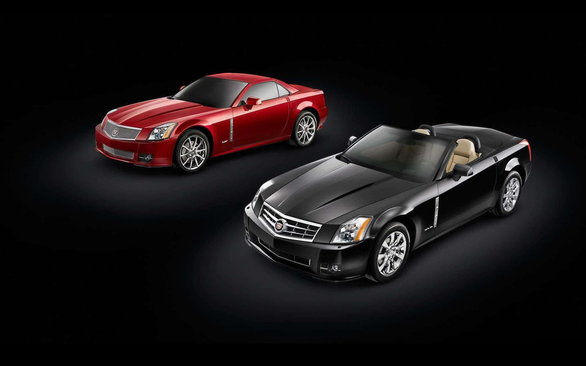 Cadillac Xlr 桌布 壁紙 — 兩輛時尚的凱迪拉克，一輛紅色轎跑車和一輛黑色敞篷車，在純黑色背景的攝影棚燈光下閃閃發光。