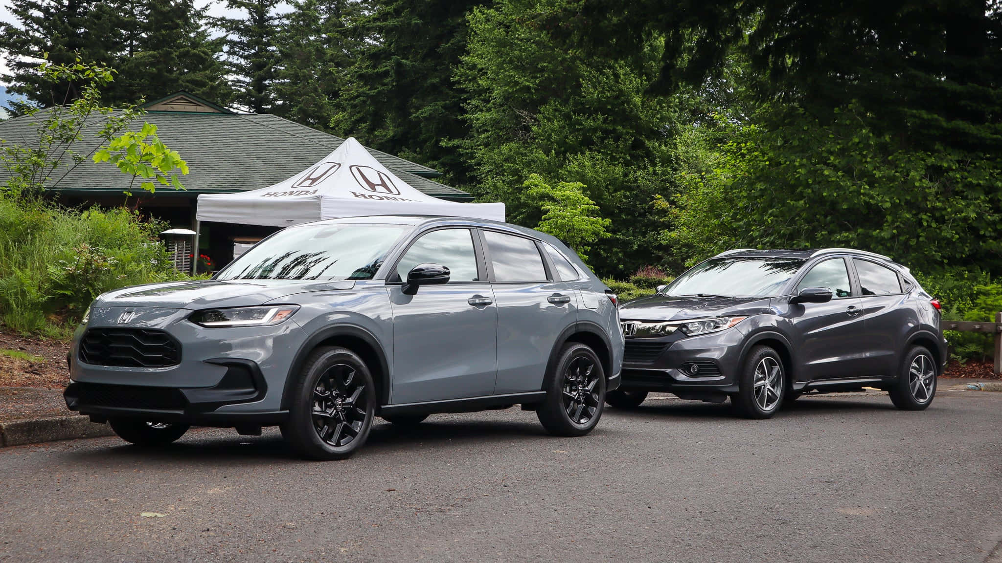 Honda Hr-v 桌布 壁紙 — 兩輛時尚的灰色本田SUV停在瀝青路面上，旁邊有一個白色品牌帳篷，背景是茂密的綠樹和一棟房子。