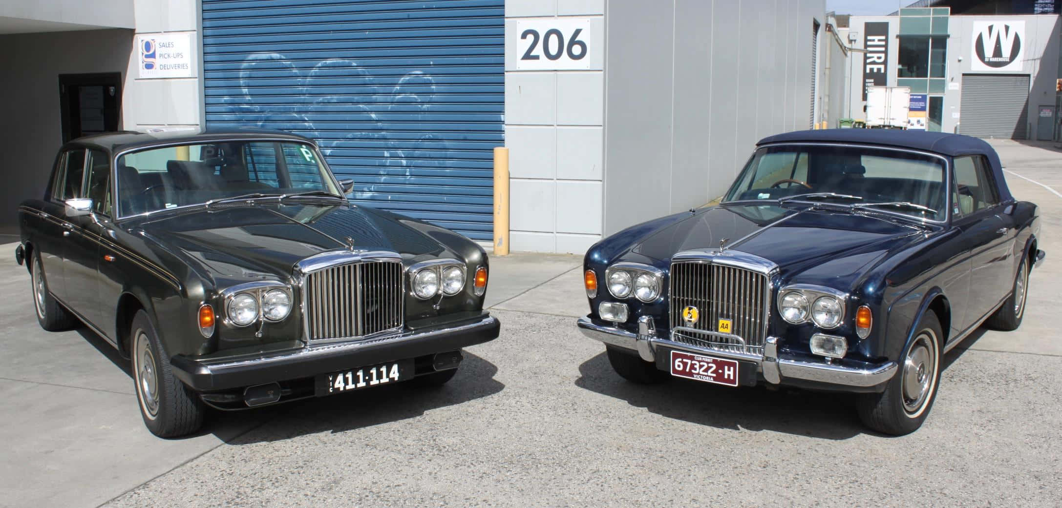 Bentley T2 桌布 壁紙 — 兩輛經典賓利汽車並排停放在帶有塗鴉的藍色車庫門前。
