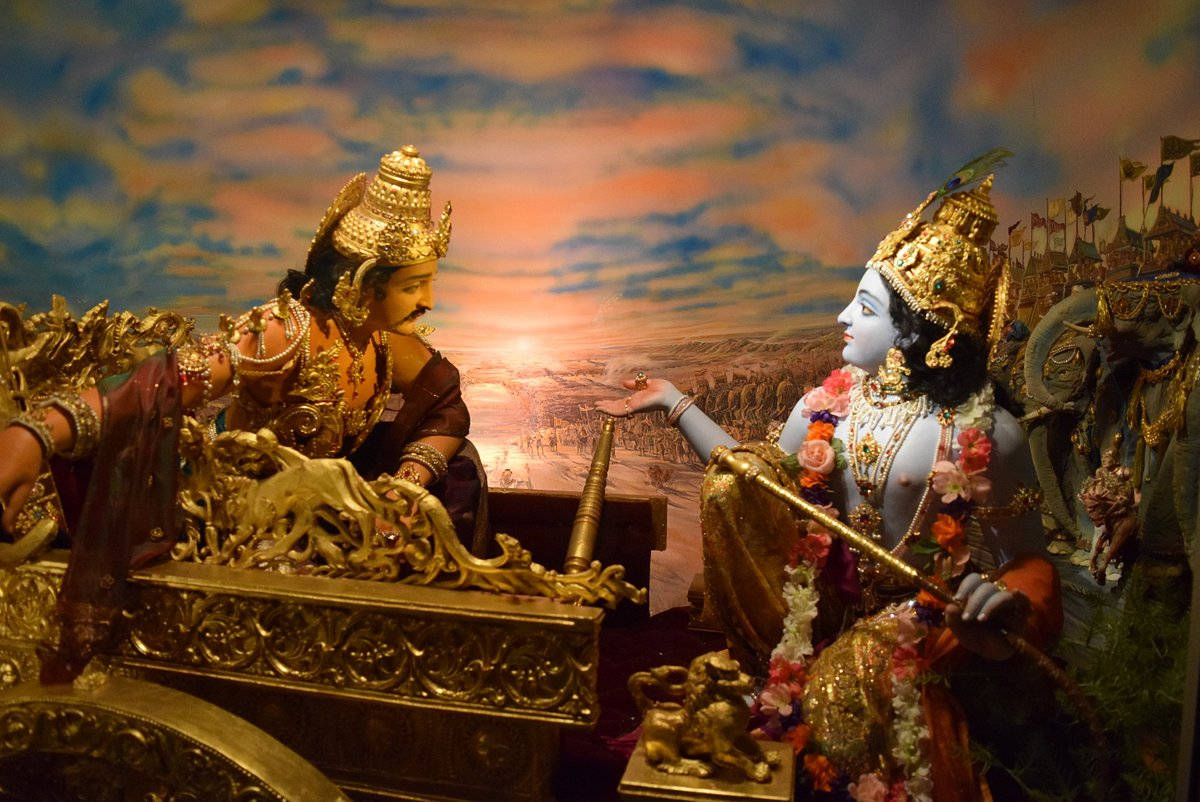 Indian 桌布 壁紙 — 兩輛金色戰車上的華麗神聖人物在繪製的戰場日落背景下相對而立。