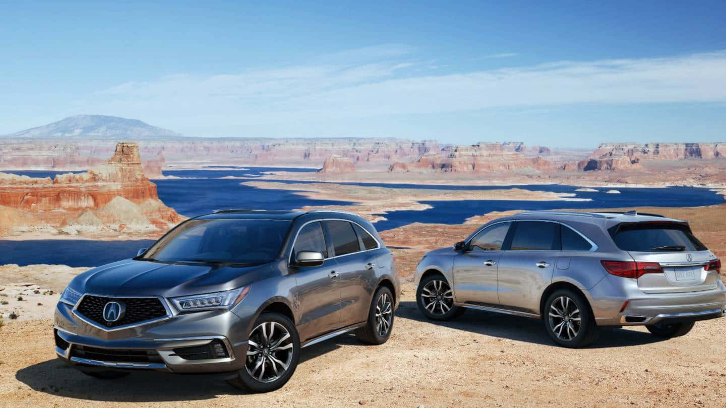 Acura Mdx 桌布 壁紙 — 兩輛銀色Acura SUV停泊在沙漠地形上，背景是廣闊的峽谷和藍色湖泊，天空晴朗。