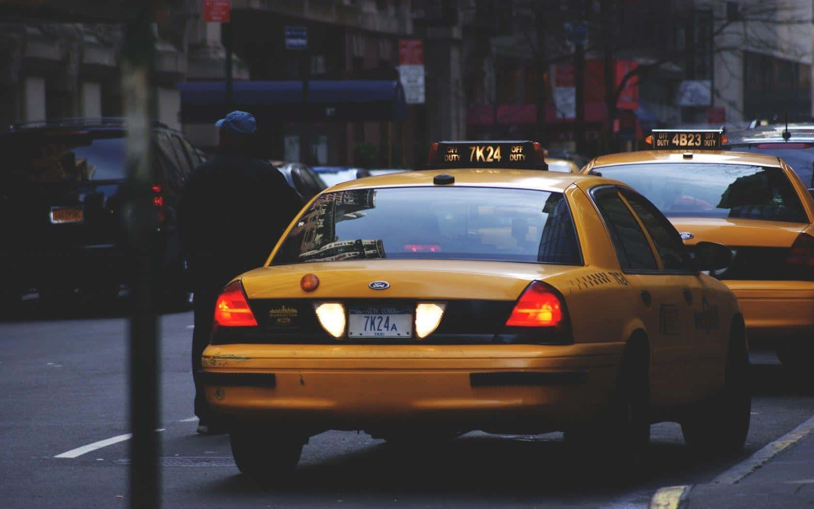 taxi 桌布 壁紙 — 兩輛黃色的紐約的士在繁華的街道上滑行，一位行人正在漸暗的光線中走過。