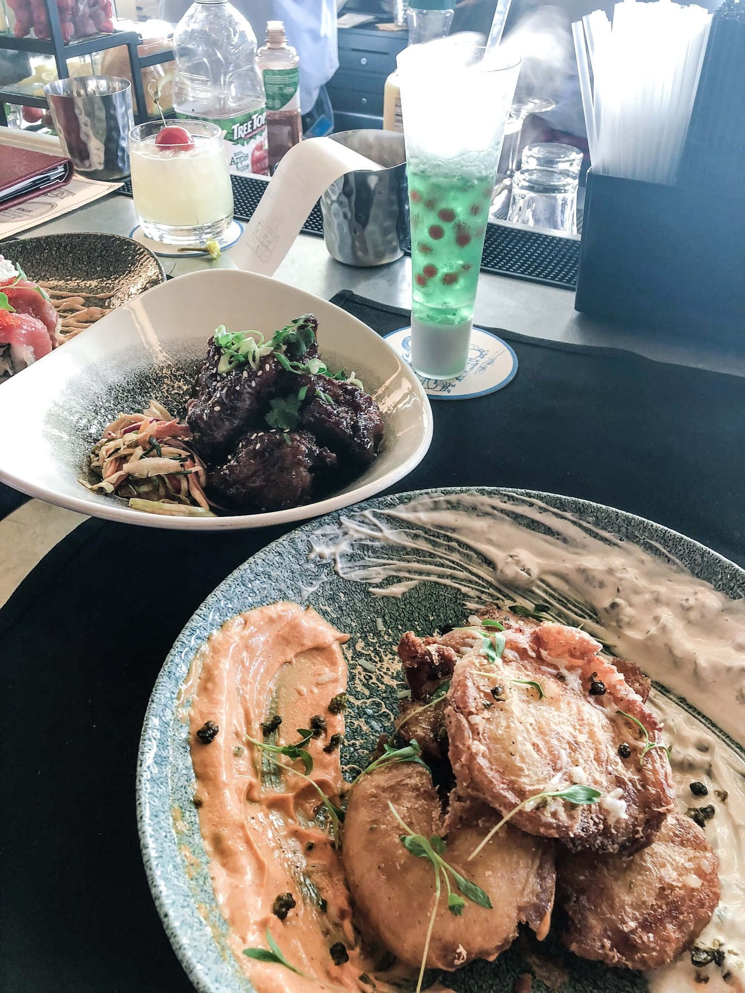 Blue Bayou 桌布 壁紙 — 兩道美食菜餚的特寫，包括炸雞和釉面肉，盛放在有紋理的盤子上，搭配色彩繽紛的醬汁和裝飾，在餐廳中呈現。