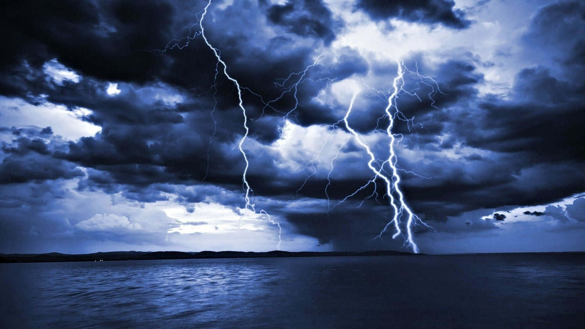 thunder 桌布 壁紙 — 兩道鋸齒狀閃電劃破風暴藍天，下方是平靜的暗色水面地平線。